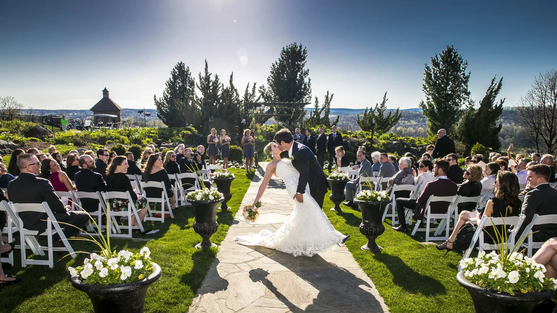 Groom dips bride and kisses her during wedding ceremony.