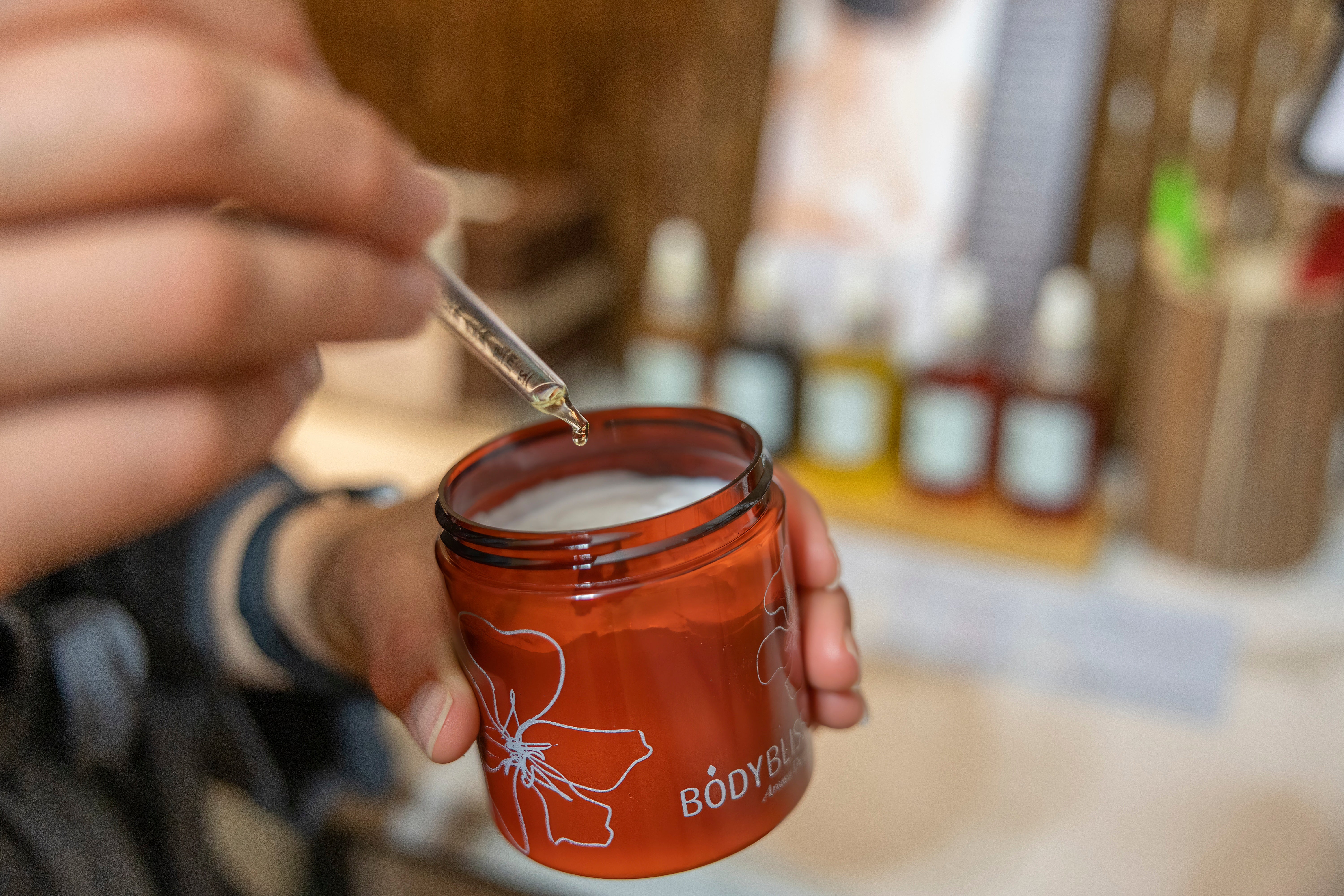 Dropper of essential oil being put in body butter