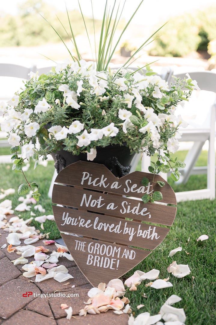 Wooden wedding sign that says pick a seat,not a side you're loved by both the groom and bride during ceremony in Ballyowen Wedding Garden.