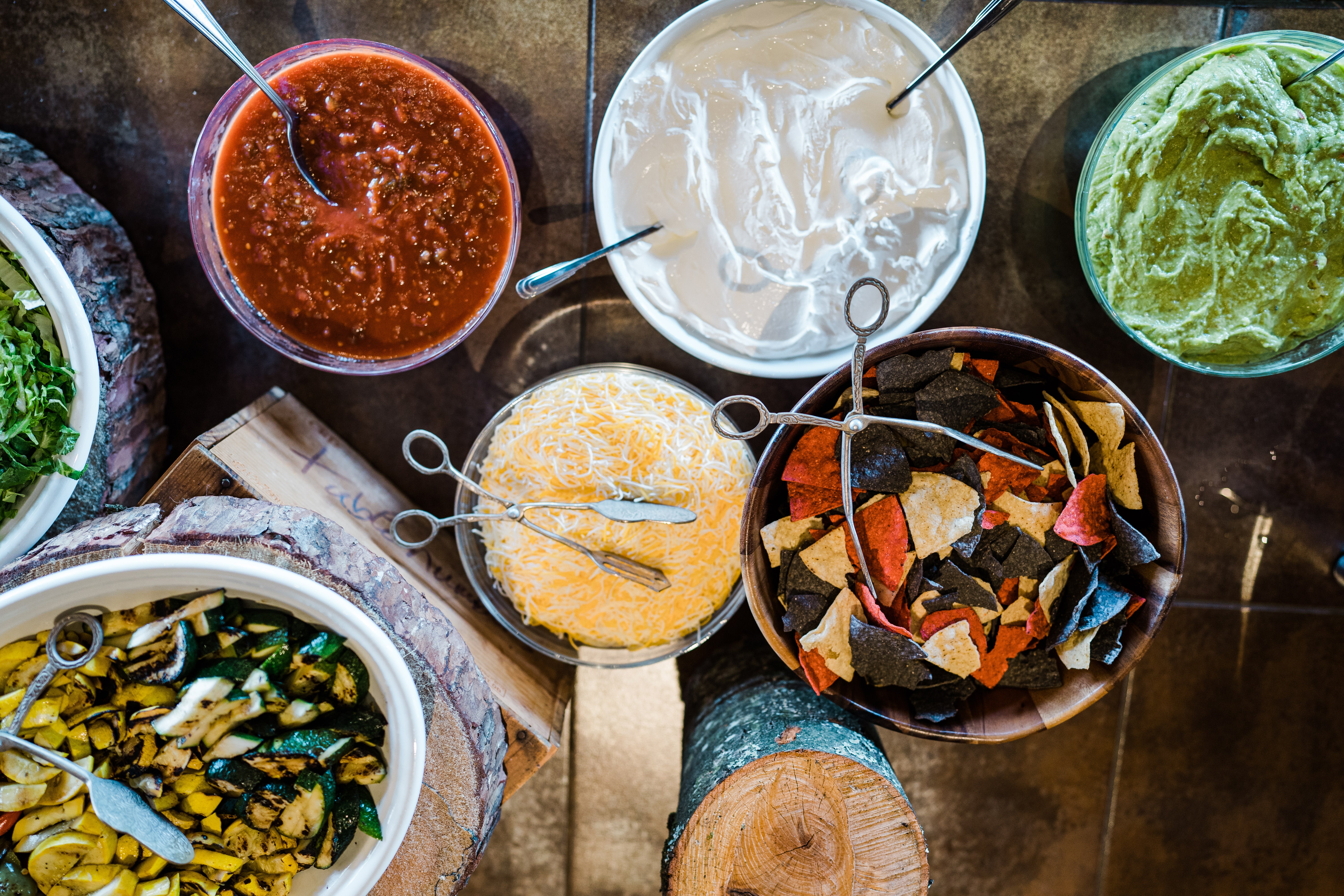 Taco station with sour cream, salsa, tortilla chips, guac and cheese. 