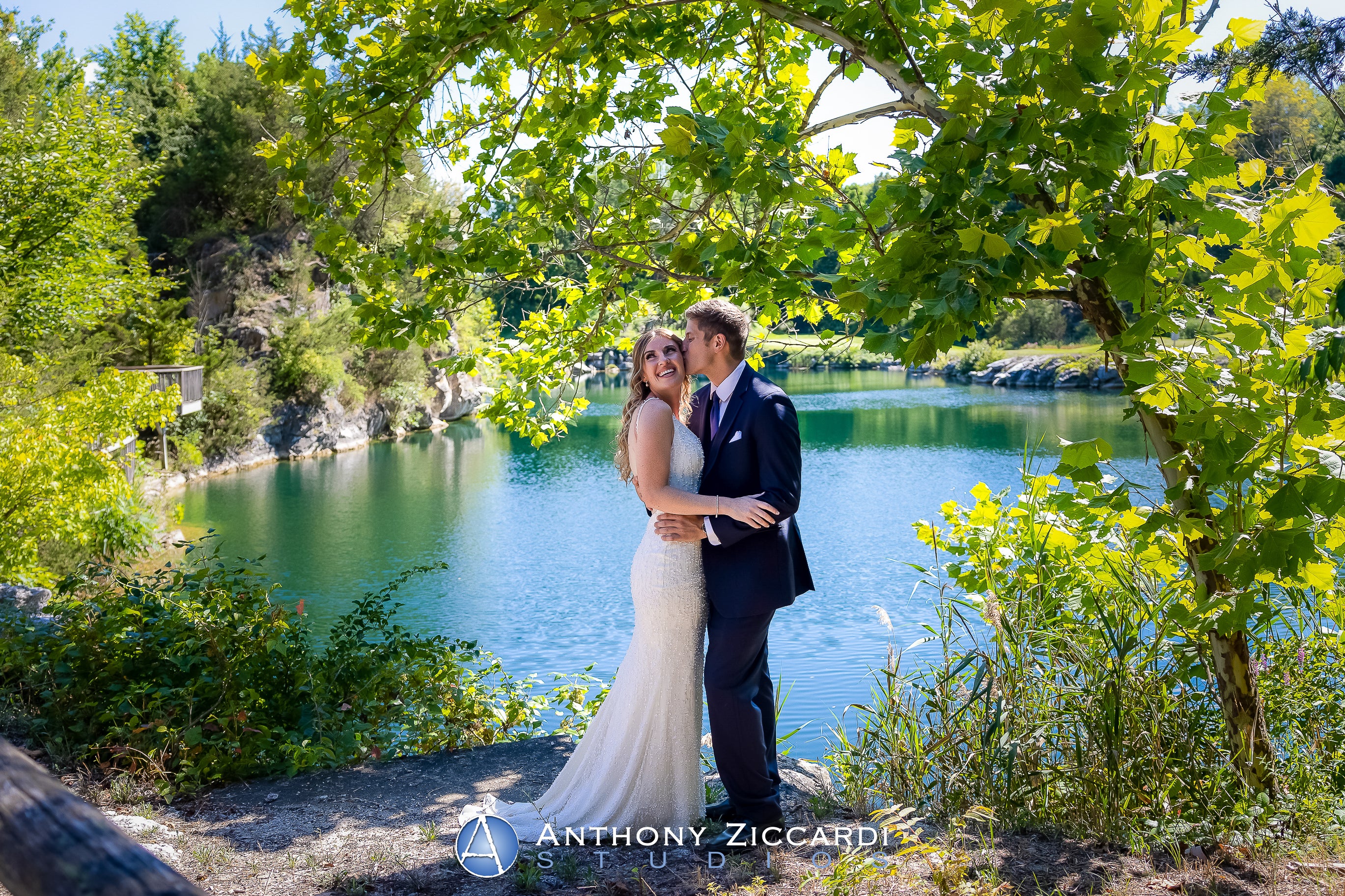 Groom kisses bride in front of Quarry Cliffs. 