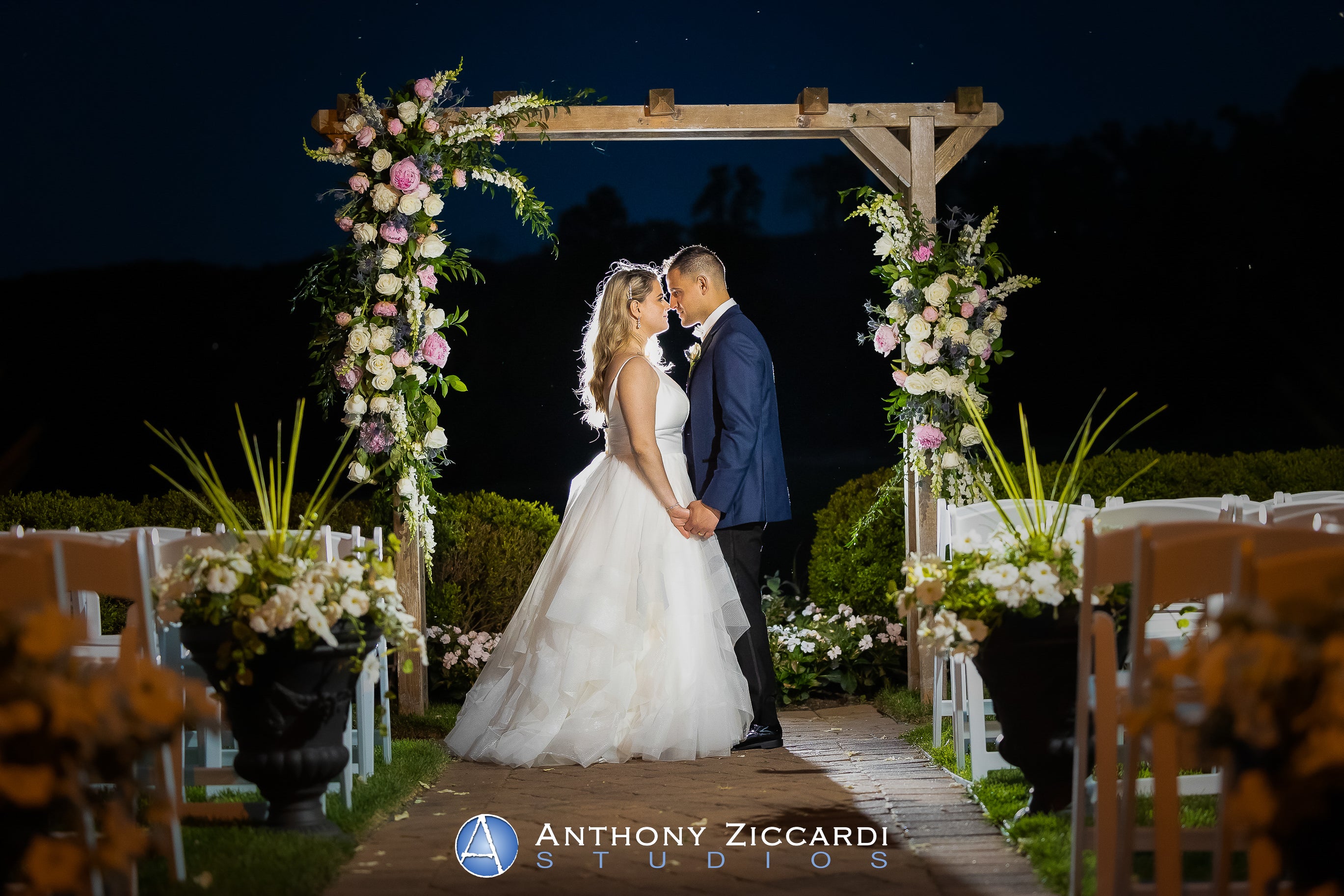 Bride and groom stand under arch in Ballyowen Wedding Garden at nighttime.
