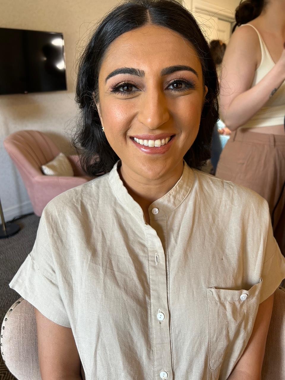 Woman, wearing white shirt, smiles at camera. 