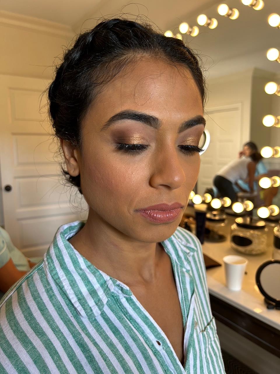 Woman closes her eyes to show off golden eyeshadow. 