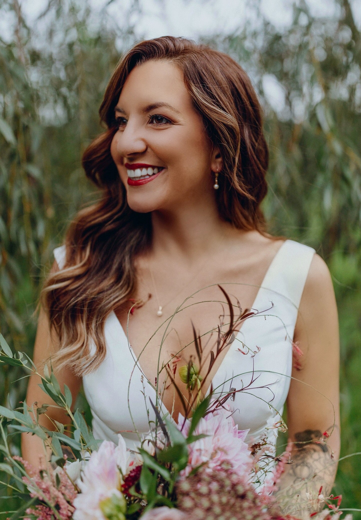 Bride looks to the side as she holds wedding bouquet. 