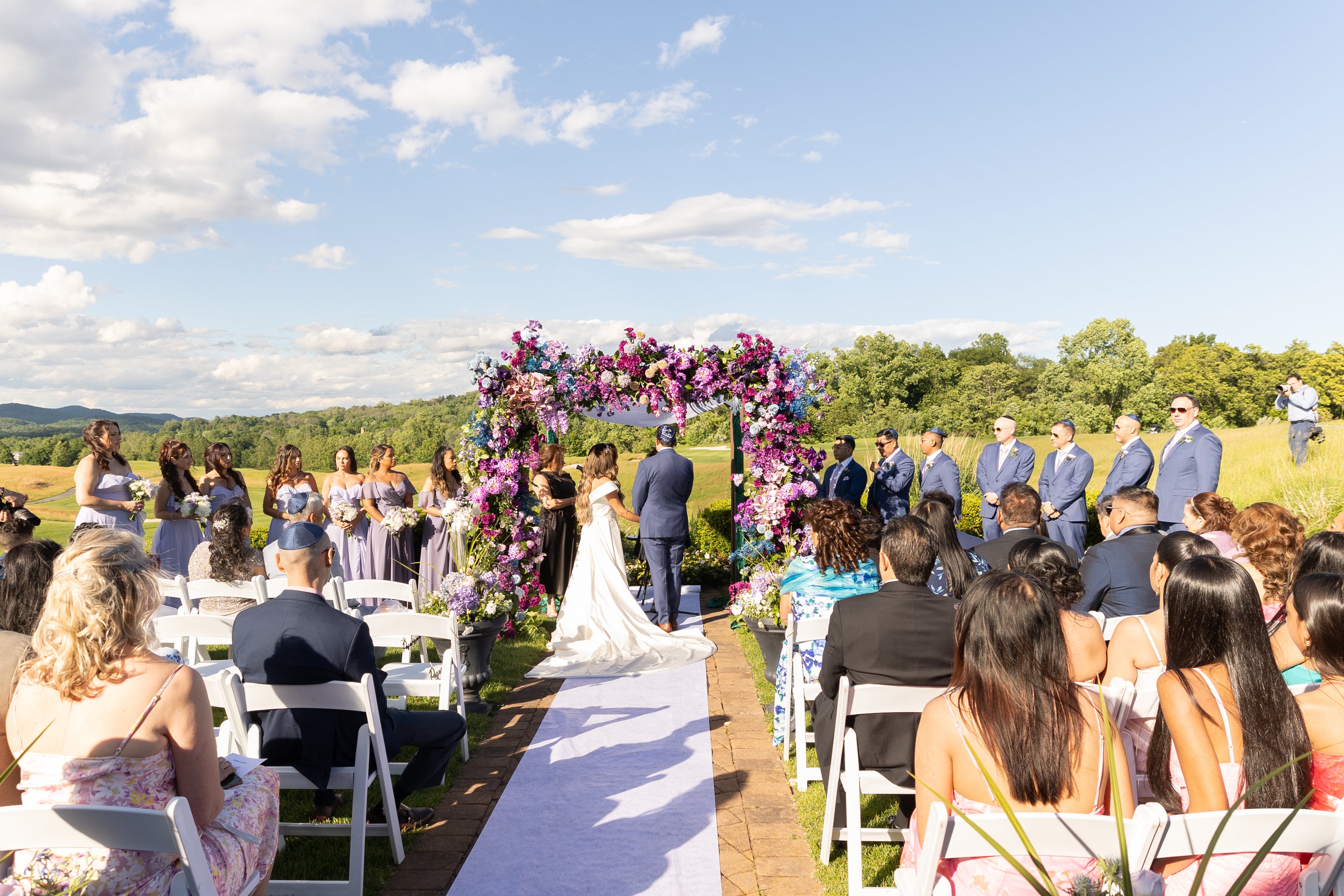 Bride and groom stand under purple flowers during their ceremony at Ballyowen wedding garden.