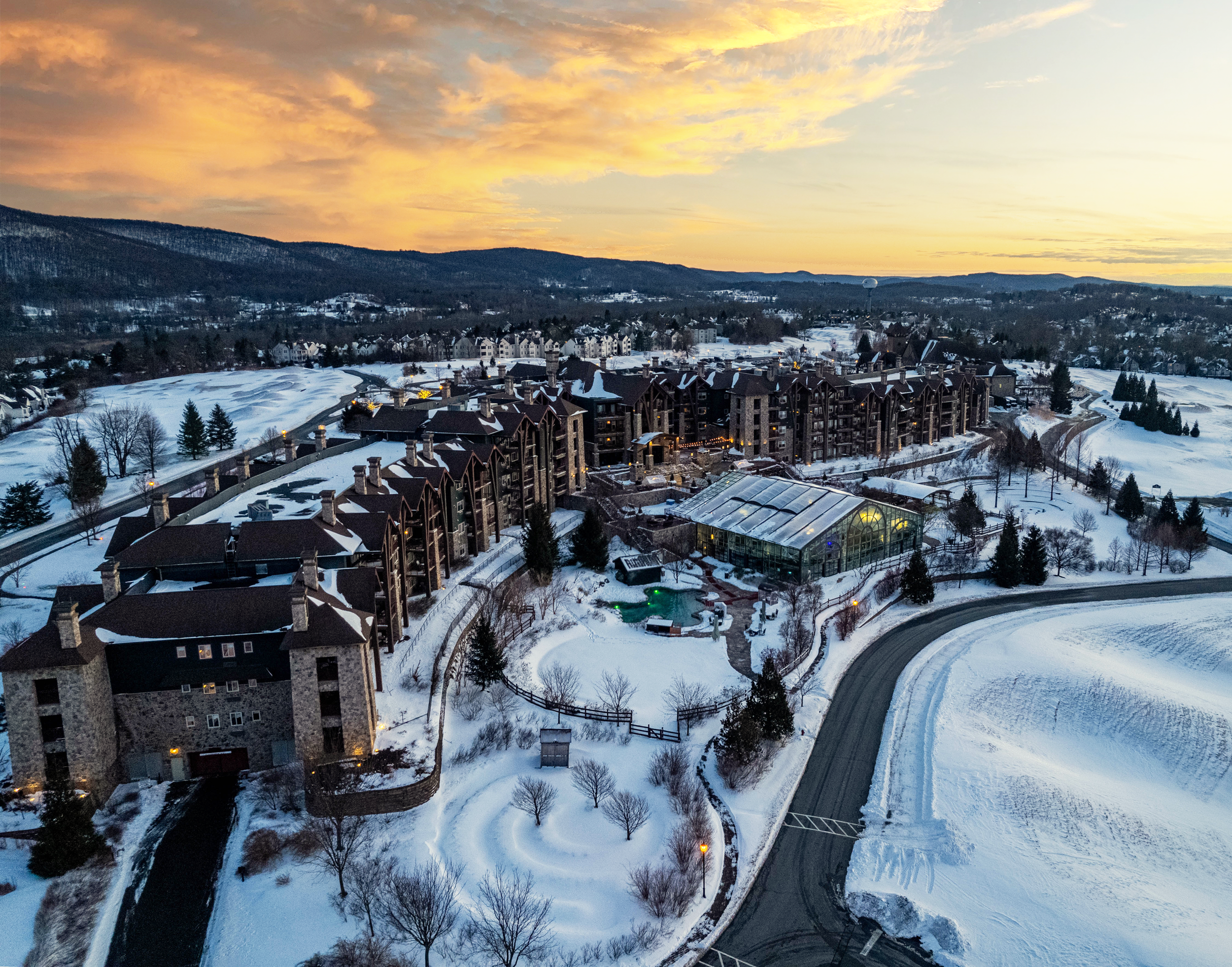Drone shot of Grand Cascades Lodge showing snow and sunset. 