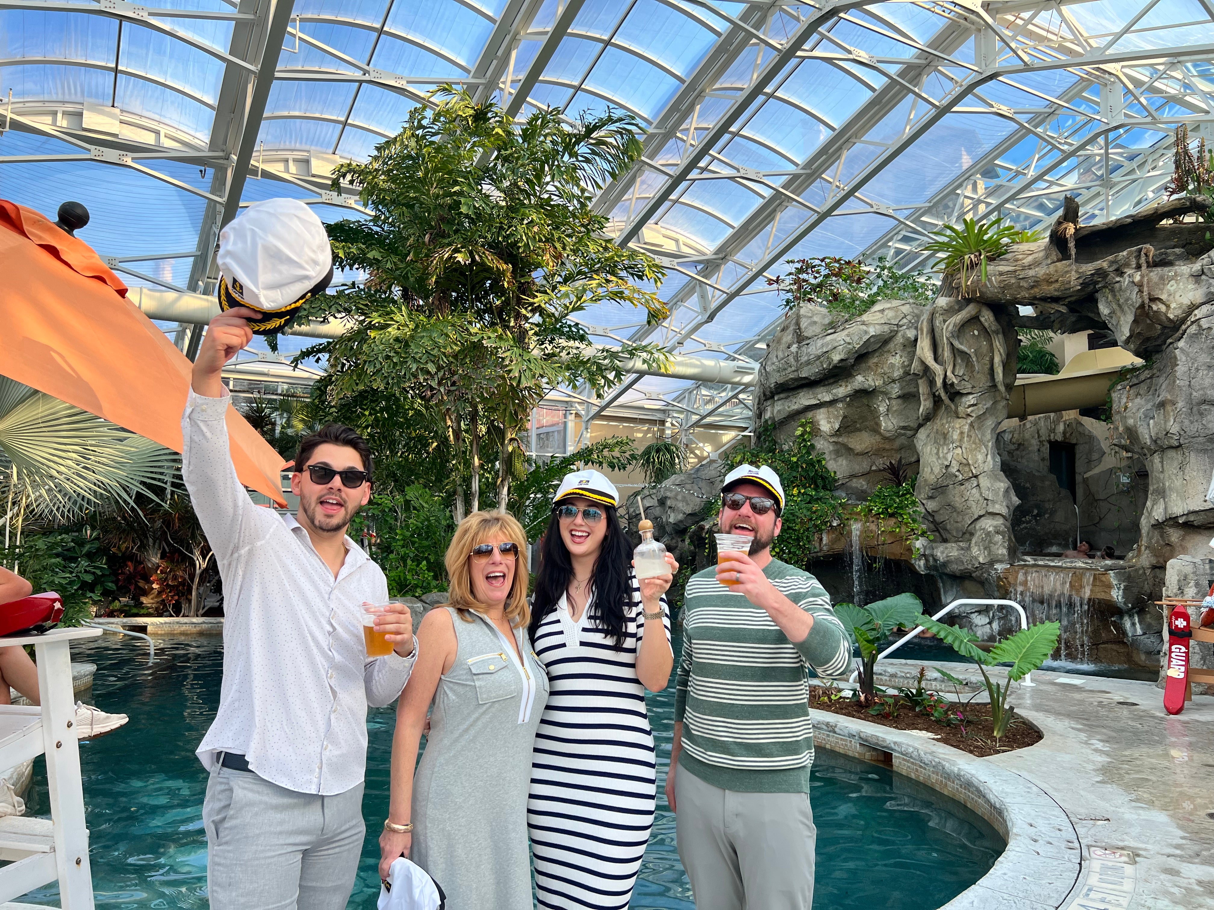 Four people stand with captain hats in Biosphere pool.