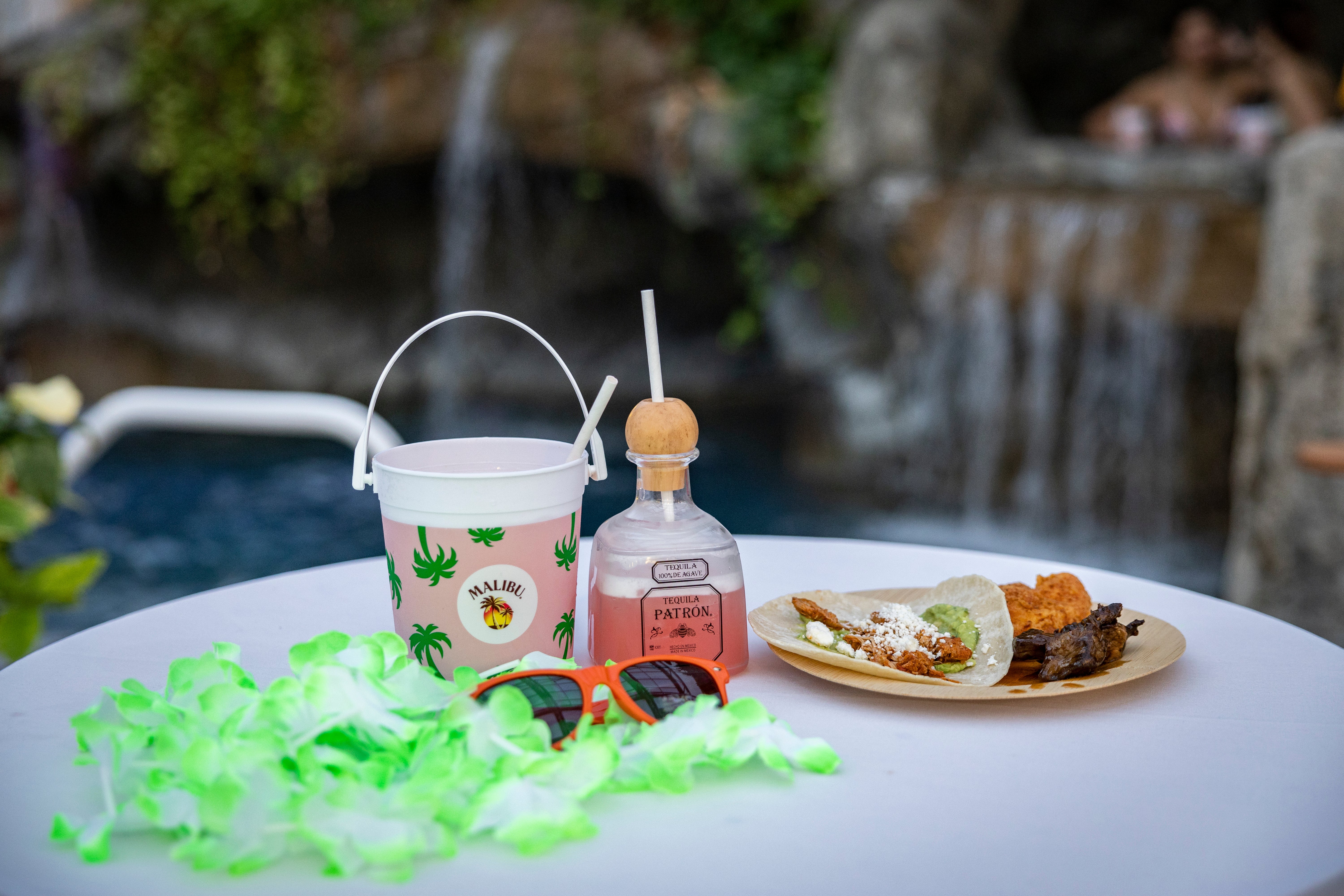 Rum bucket, tequila drink, tacos and sunglasses on table. 