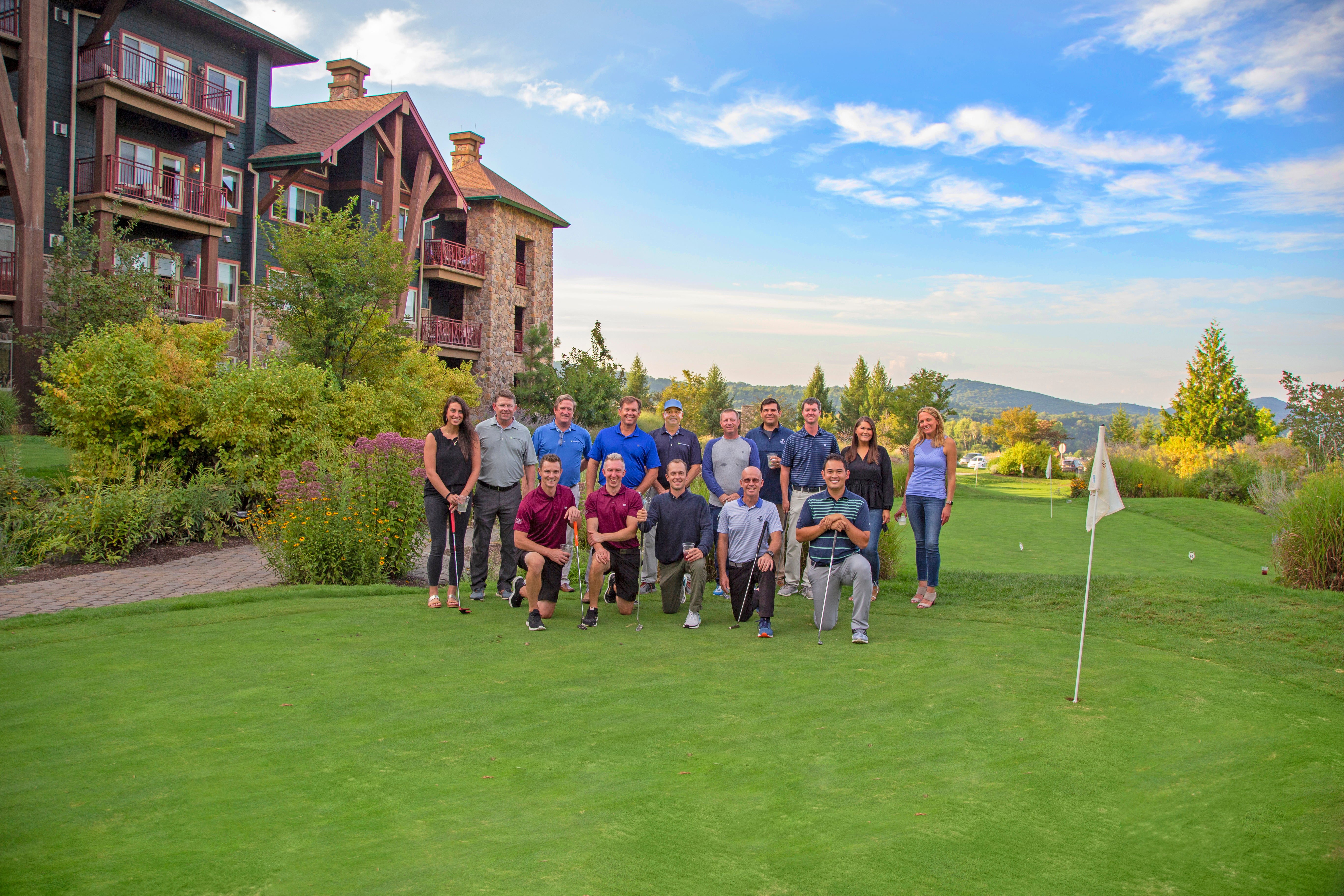 Group of people pose for photo on putting course.