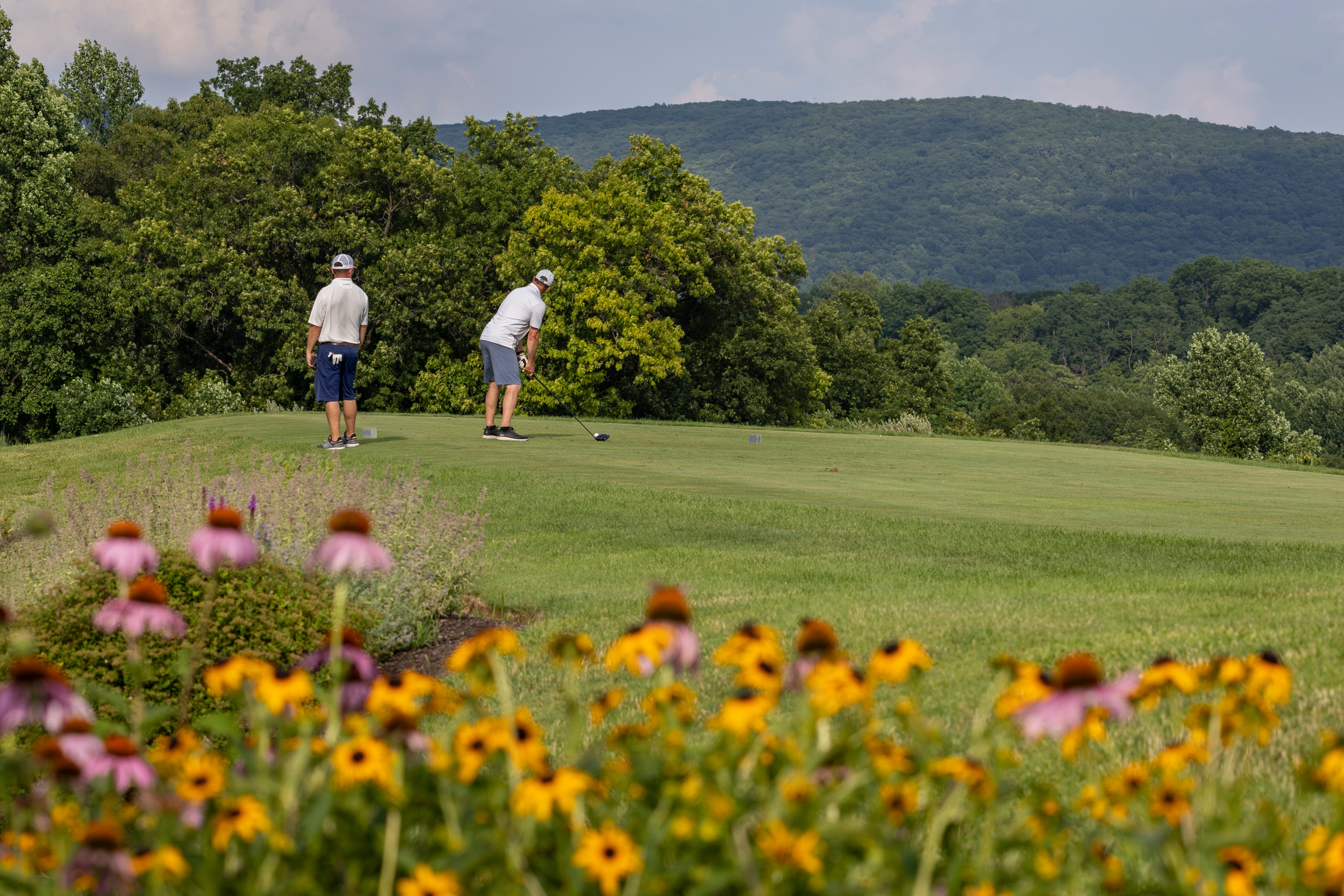 Golfers putting on Ballyowen Golf Course with mountains in background.