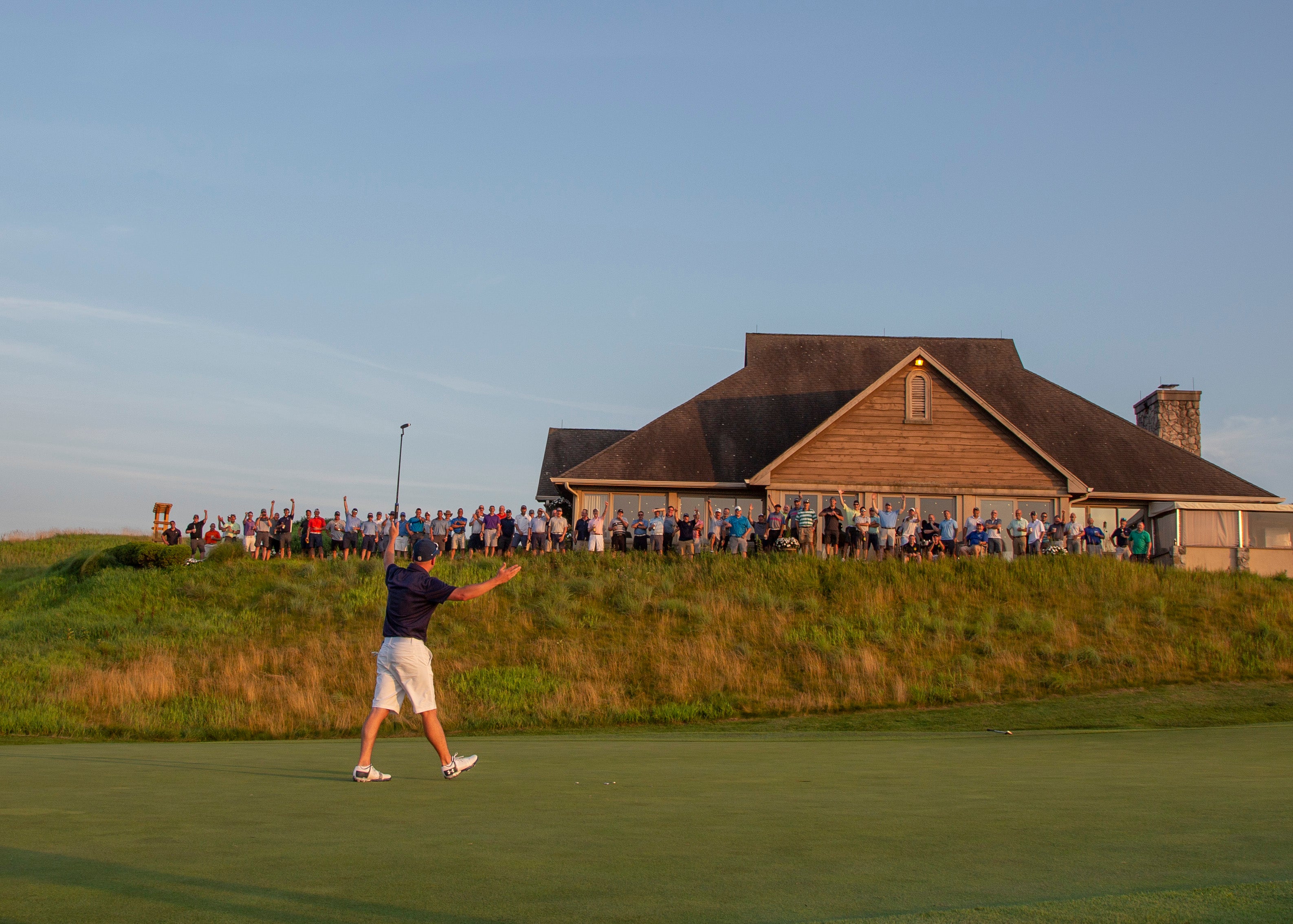 Golfers throws hands up in the air as he celebrates towards the crowd. 