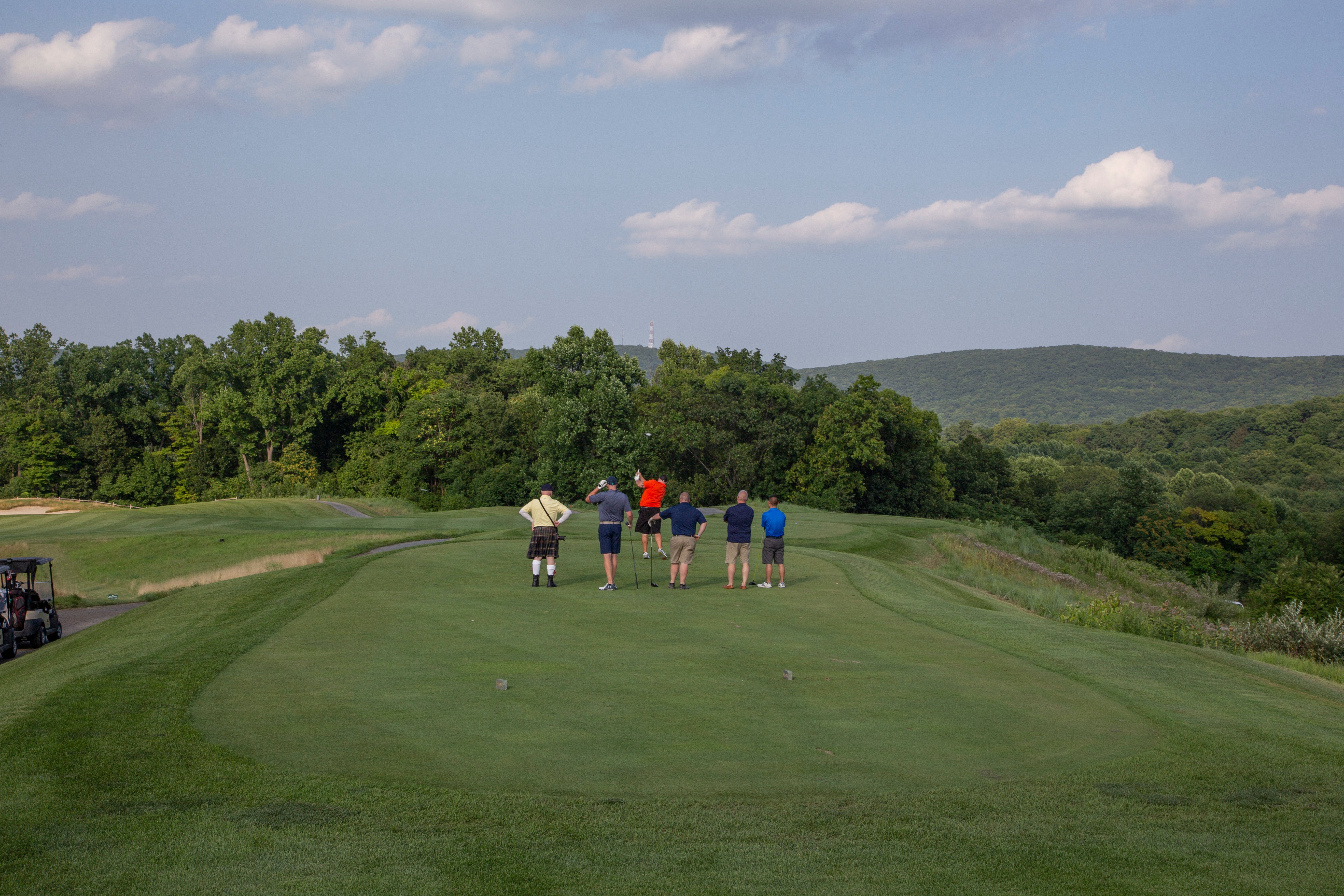 Golfers looking out over tree range. 