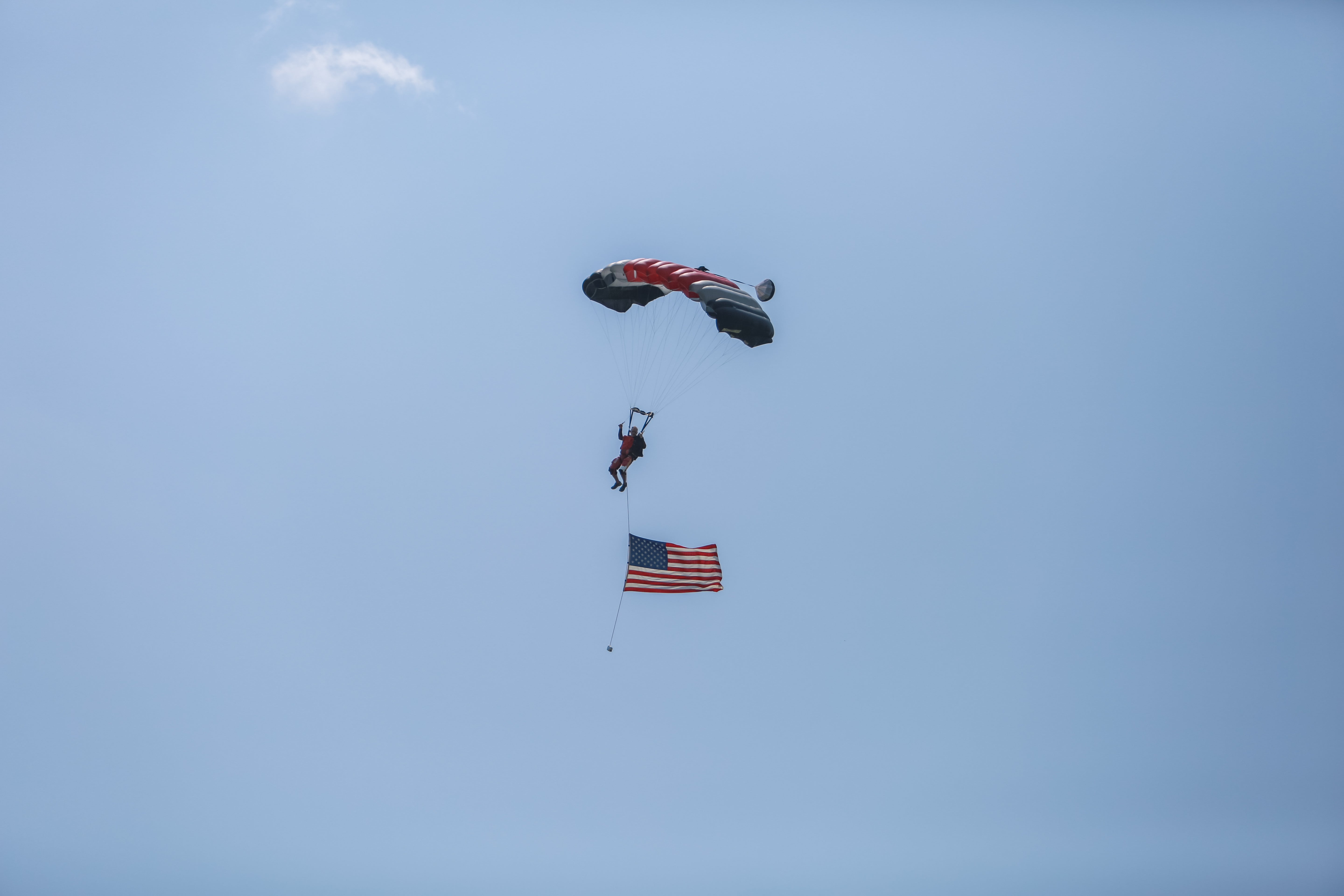 Man parachuting in air with American flag. 
