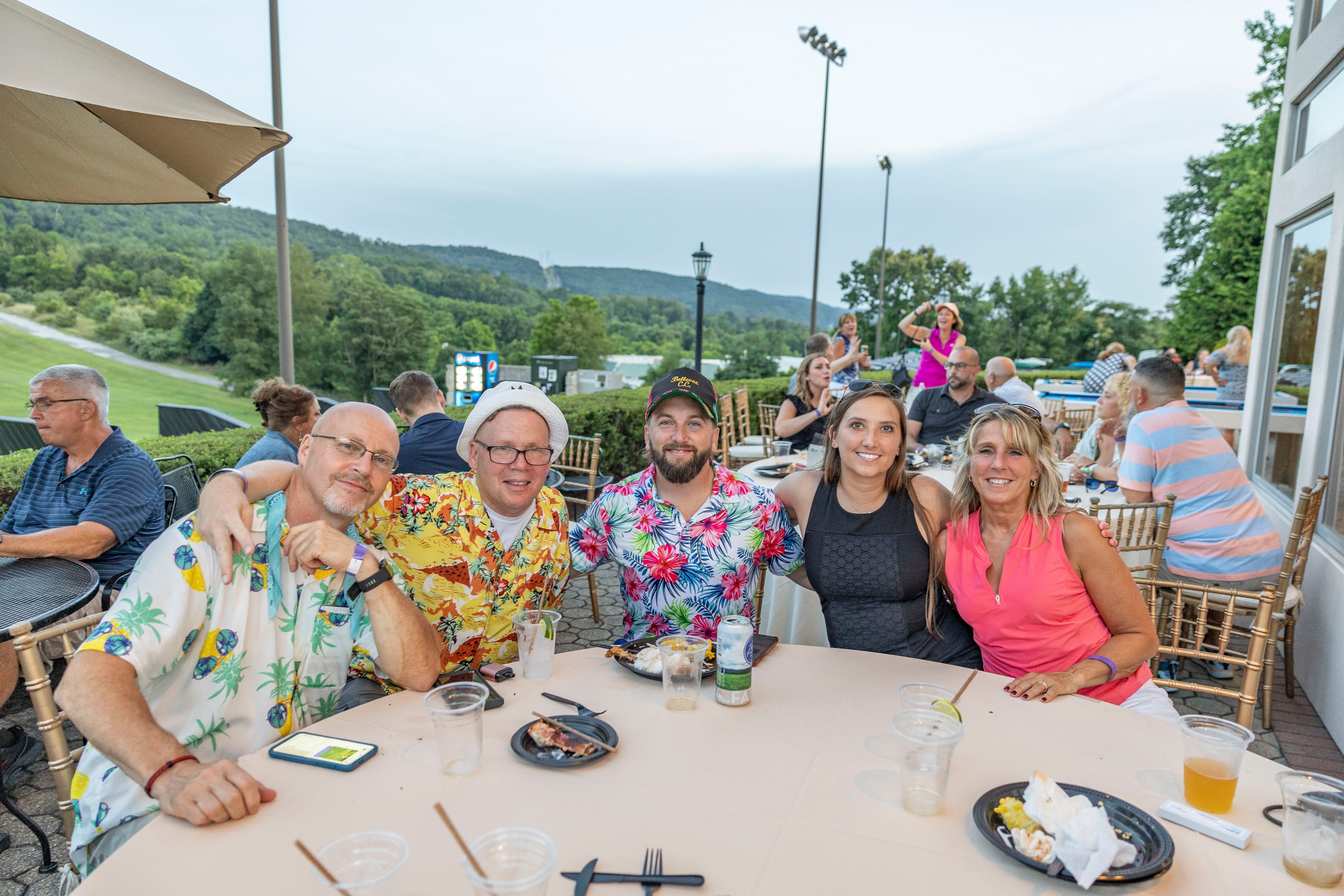 Group of people sitting at table with mountain view behind them.