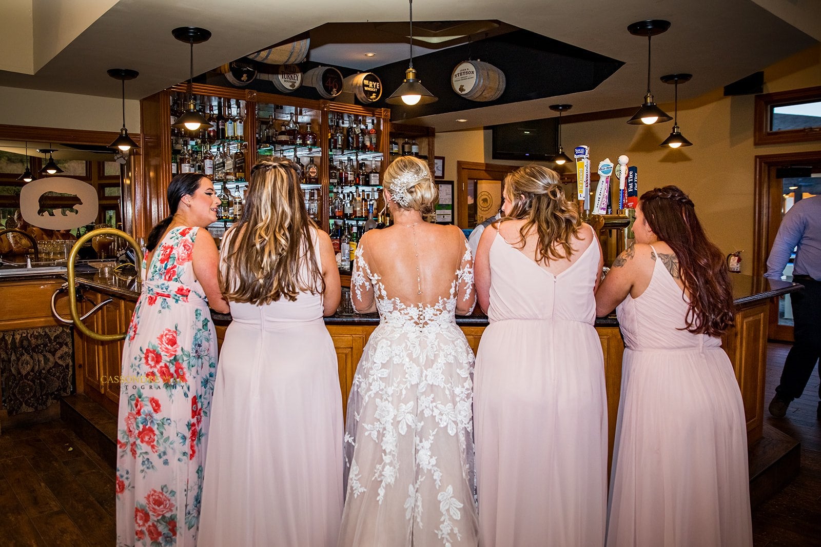 Bride and bridesmaids stand at Bear Den Grille bar during Black Bear cocktail hour.