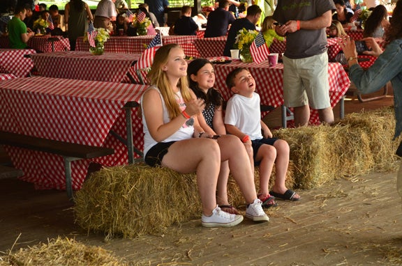 Three children sitting on hay bales.