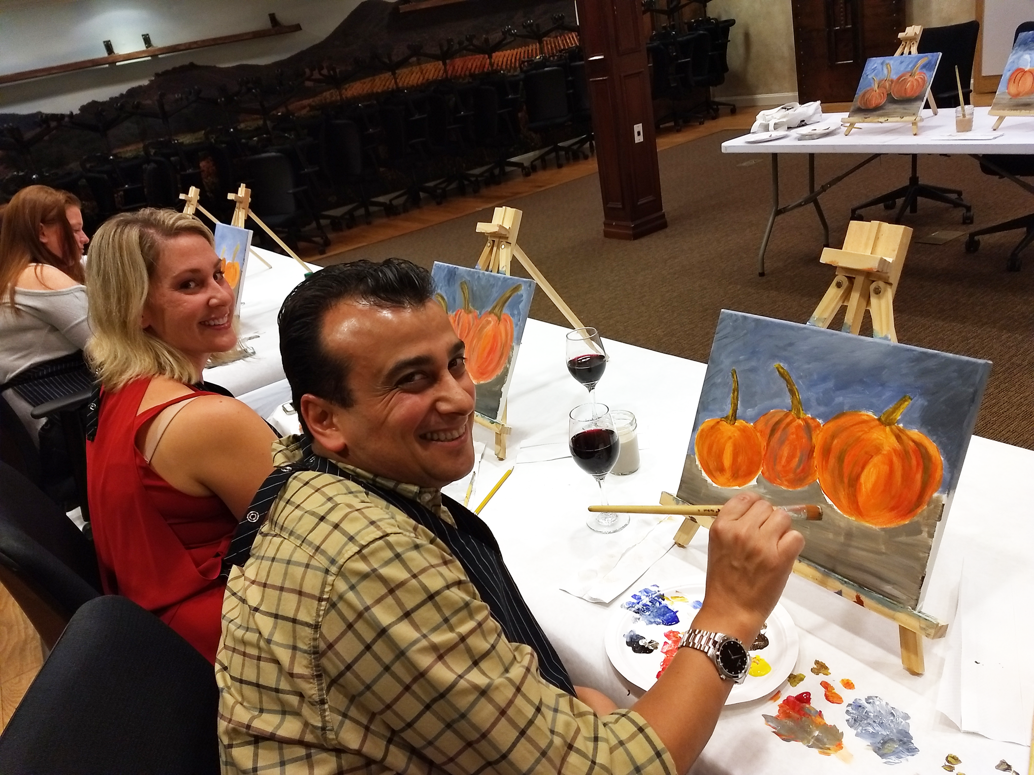 Group painting pumpkins on canvas. 