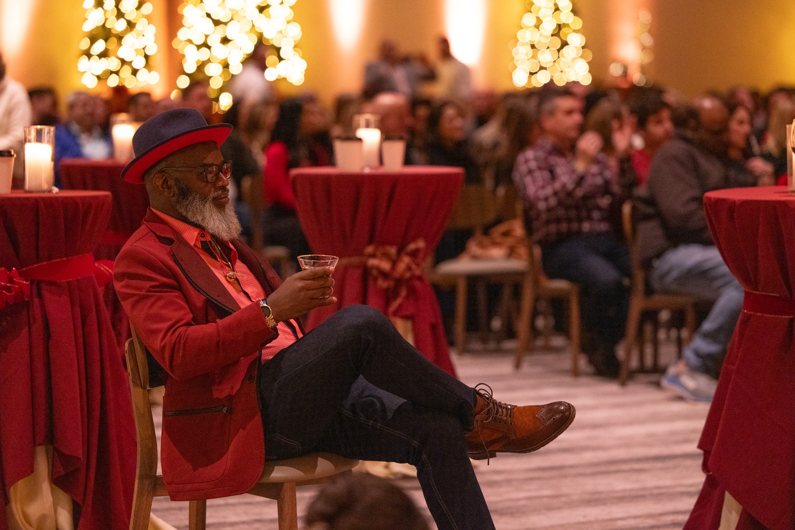 Man in red tux sitting in chair enjoying music. 
