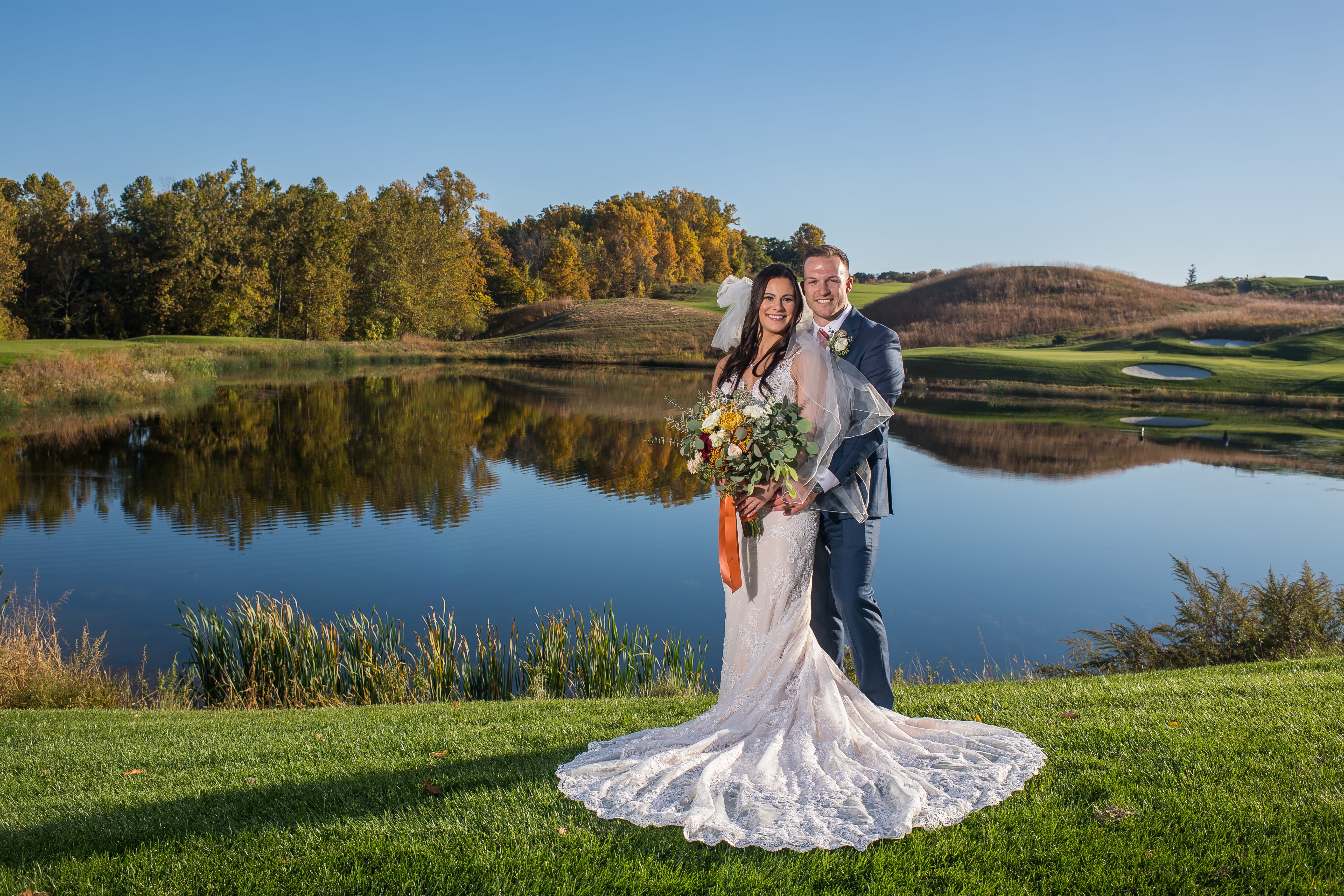 Bride and groom stand by water at Ballyowen Golf Club. 