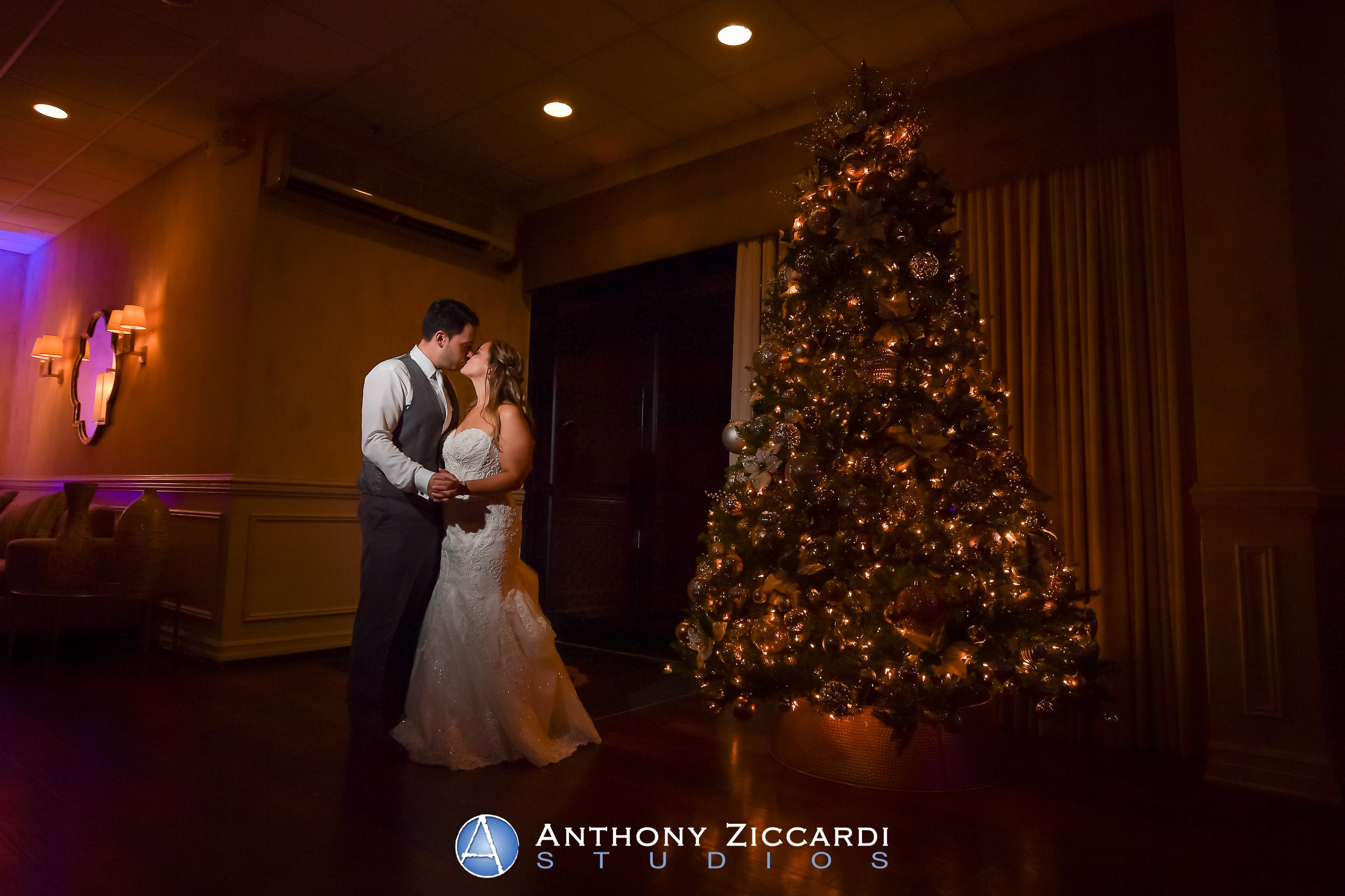 Bride and groom look at one another standing next to a Christmas tree in Diamond Ballroom.