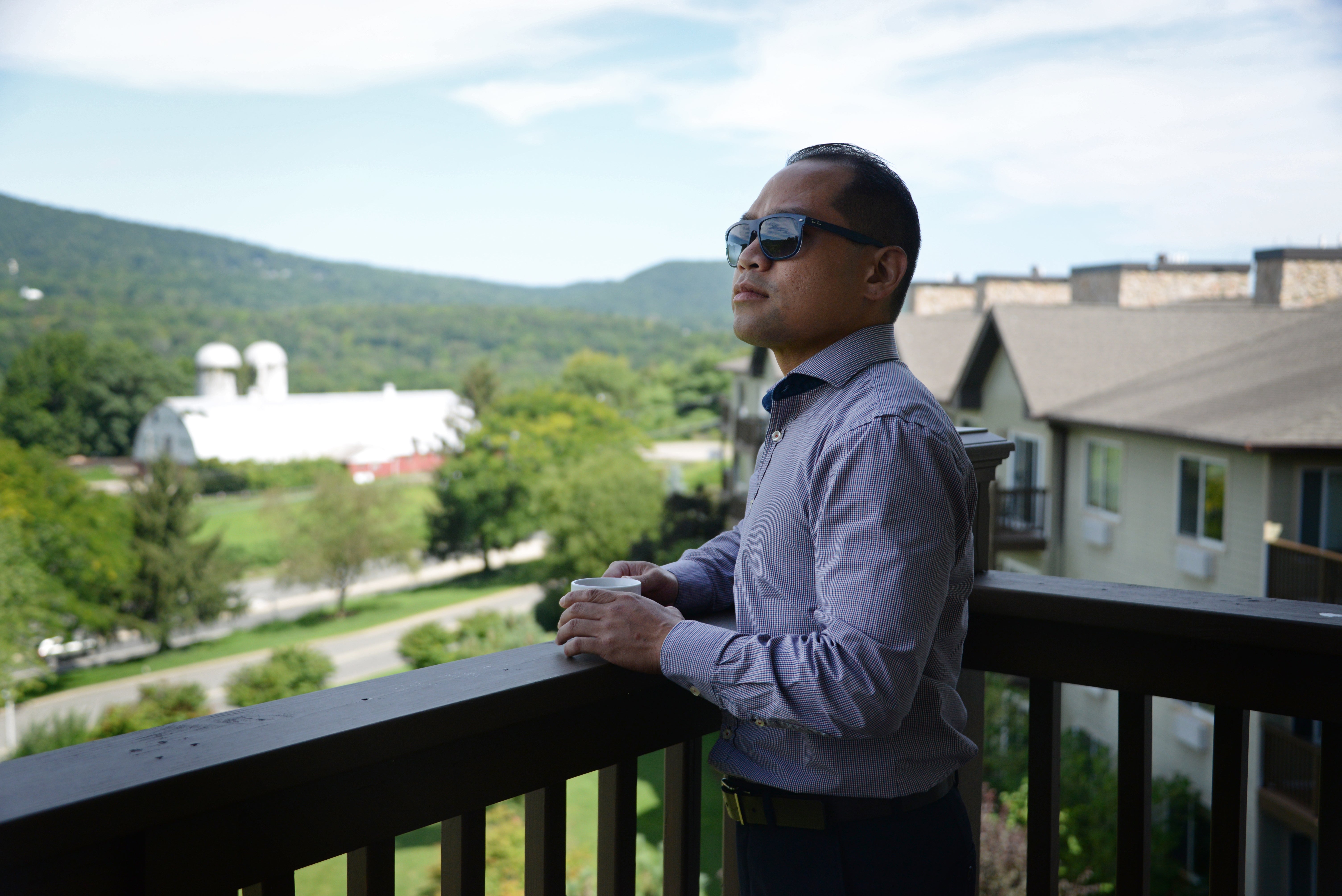 Man standing on Minerals Hotel balcony drinking coffee