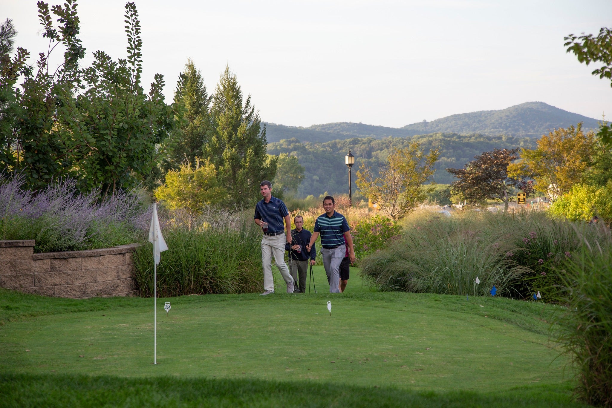 Men walking onto natural grass putting course. 