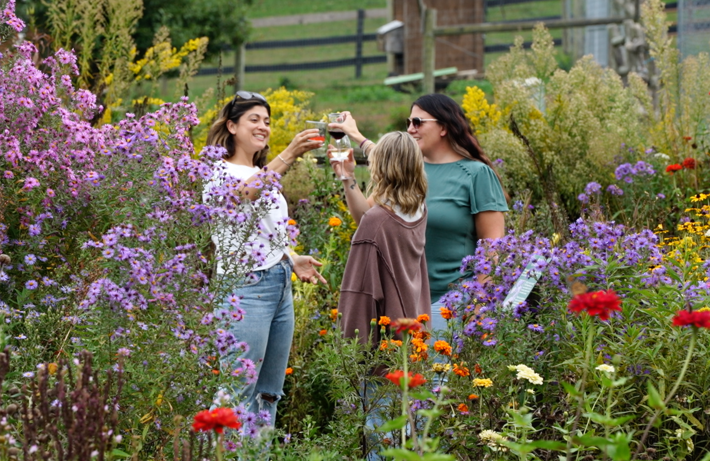 Three friends cheersing their drinks while surrounded by flowers.