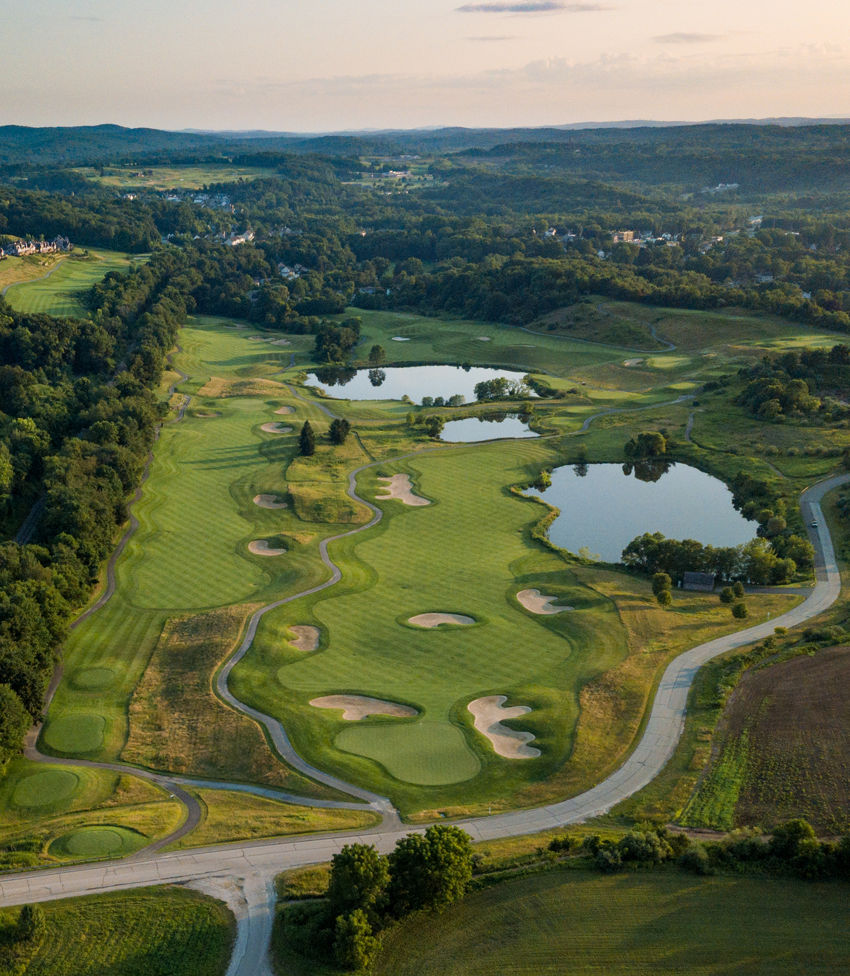 Aerial view of Wild Turkey Golf Course at Crystal Springs Resort, featuring rolling fairways, sand bunkers, ponds and wooded hills.