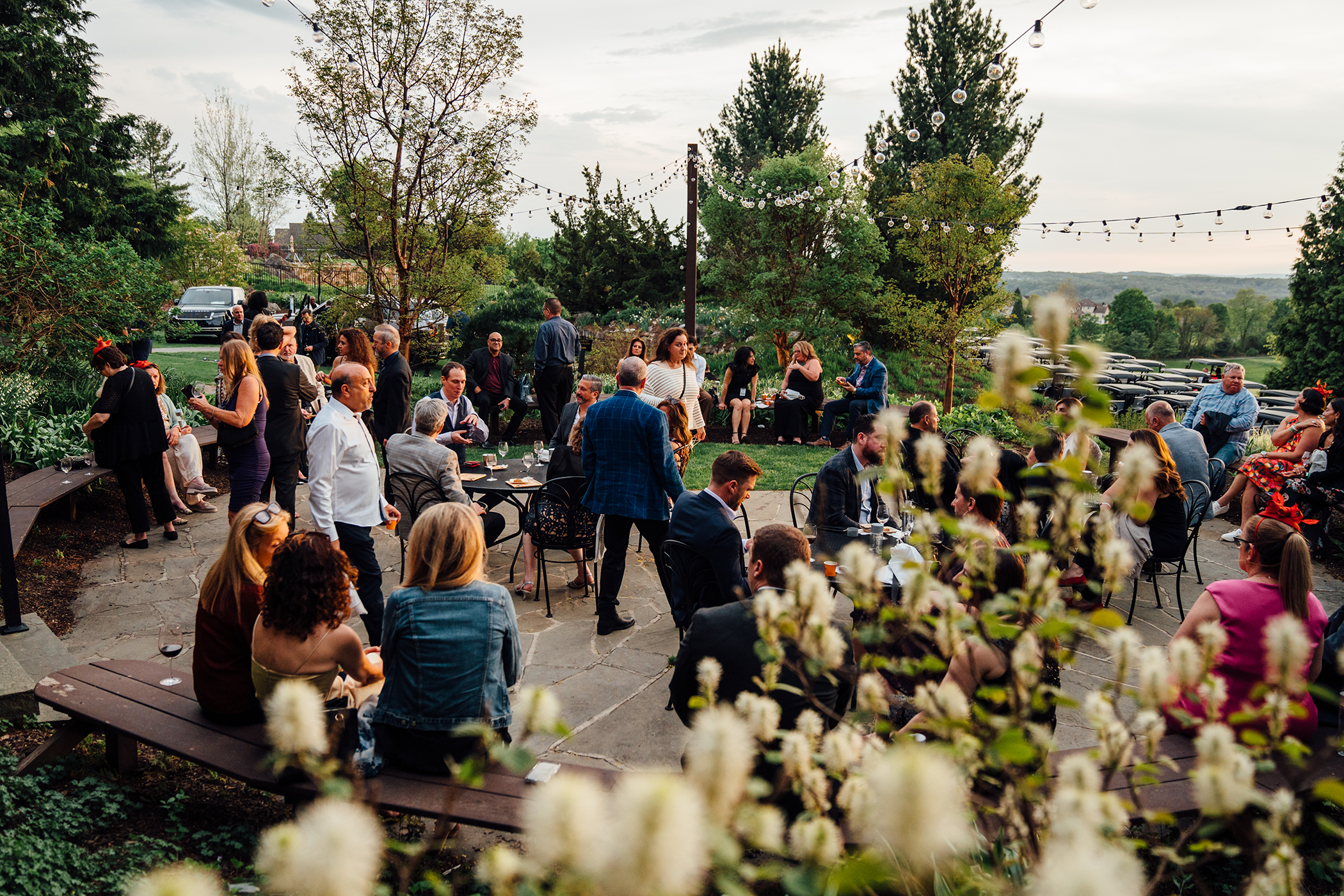 Guests mingle at an outdoor reception surrounded by lush gardens and trees at Crystal Springs Resort.