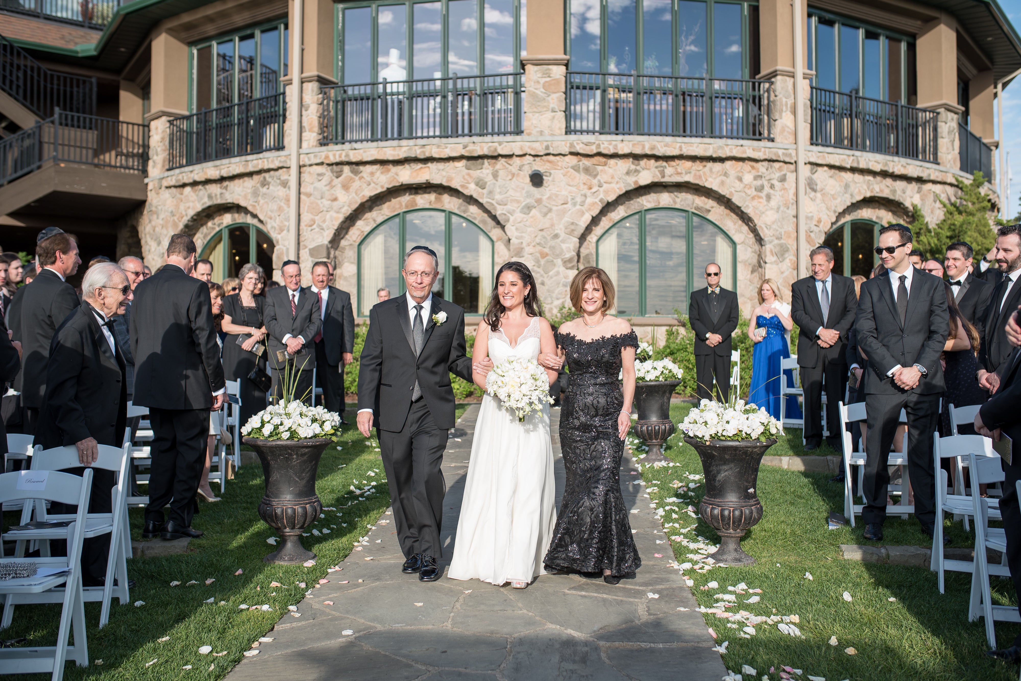 Bride walking down aisle with parents at the wedding garden