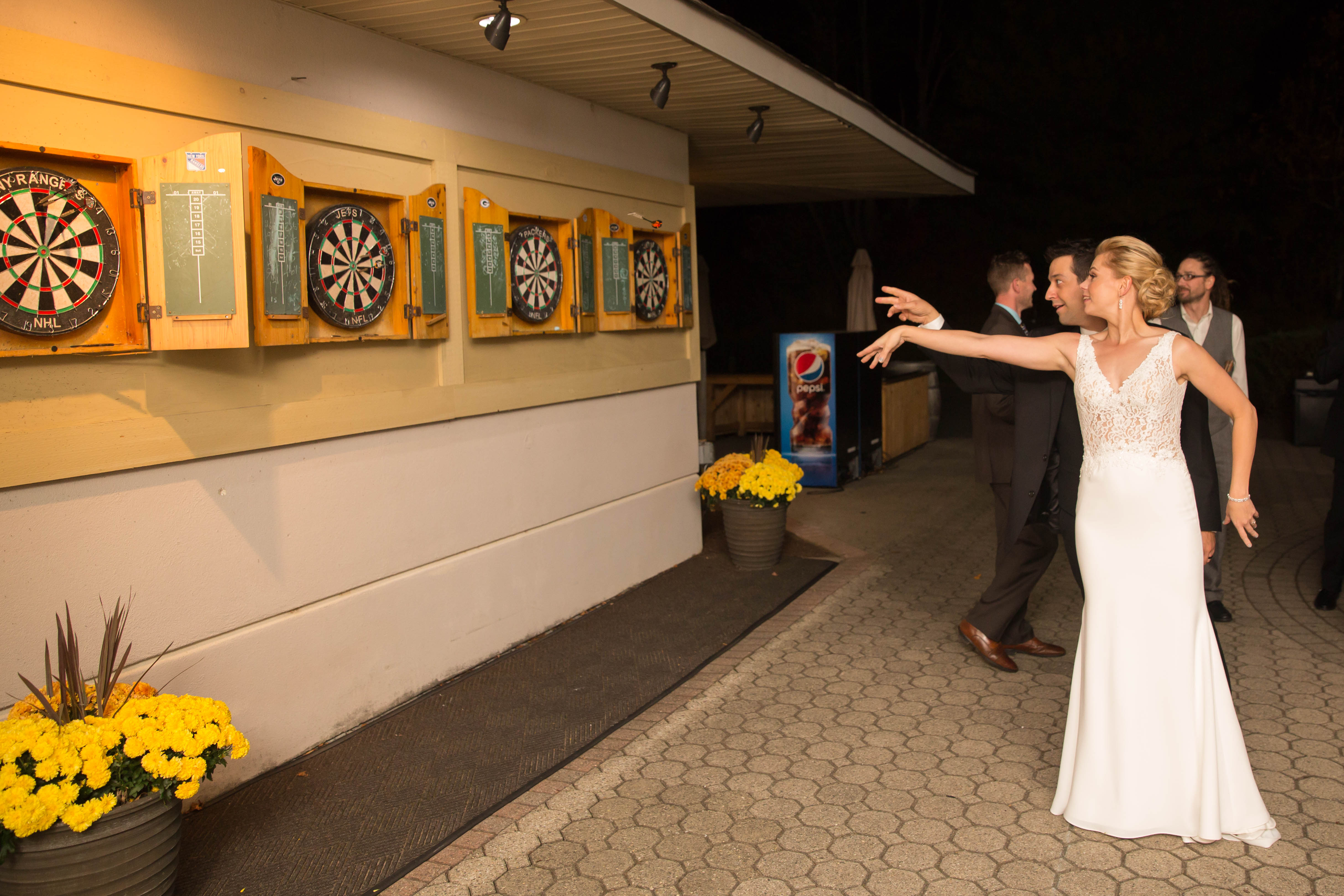 Bride playing darts at wedding reception