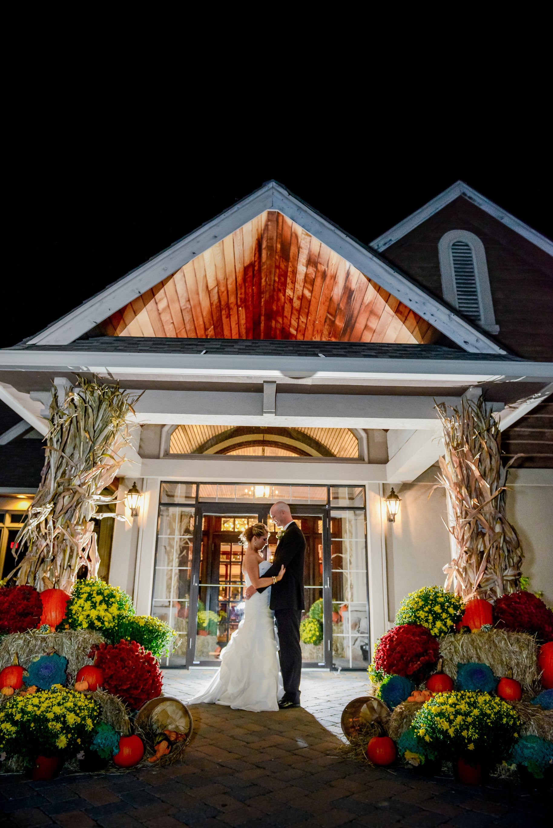 Bride and groom holding one another surrounded my fall flowers and mums.