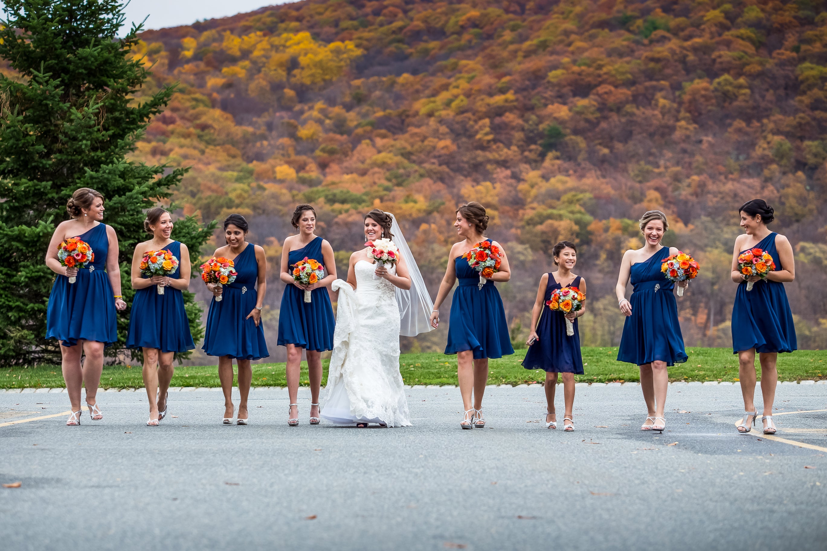 Bride walking with her bridesmaids, wearing short blue dresses, among the fall mountains.