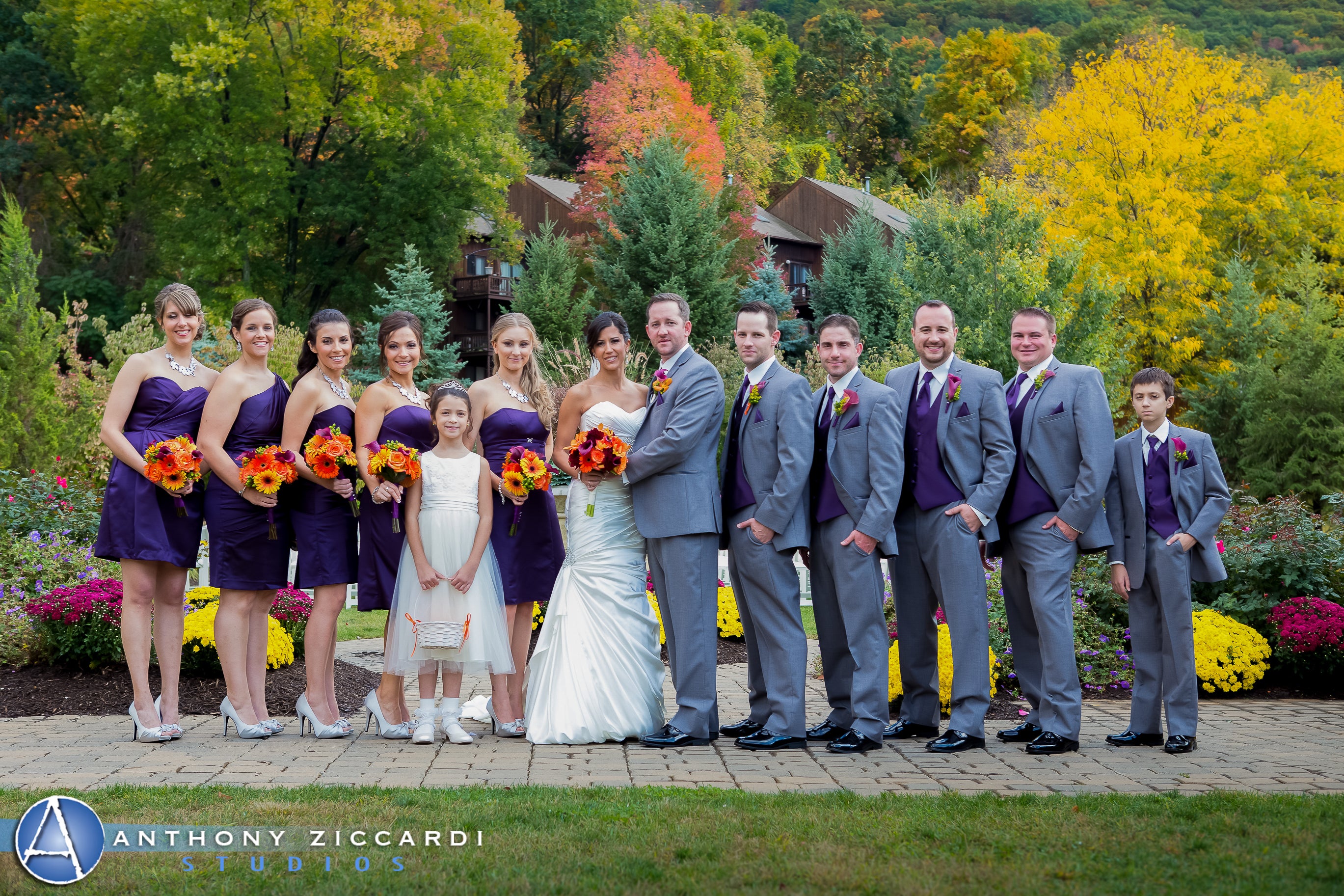 Wedding party featuring bride, groom, bridesmaids in purple short dresses and groomsmen in grey tuxes.