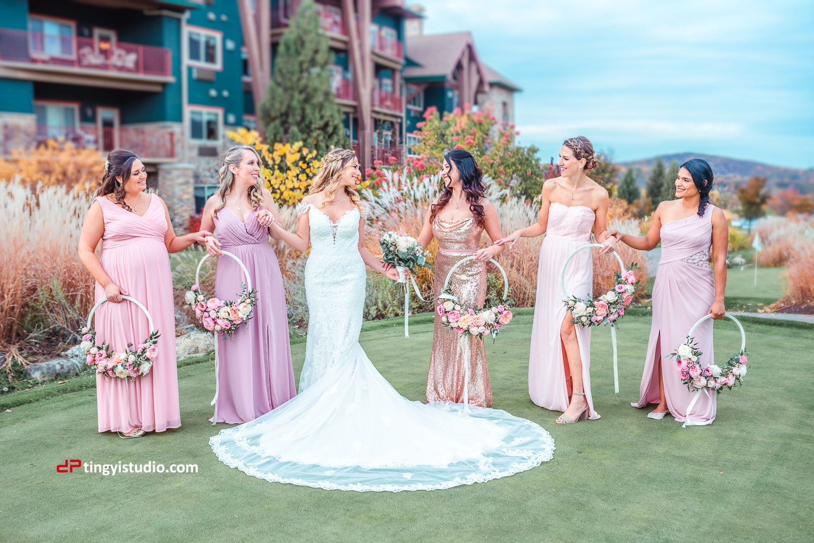 Bridesmaids wearing pink dresses stand hand in hand with the bride.