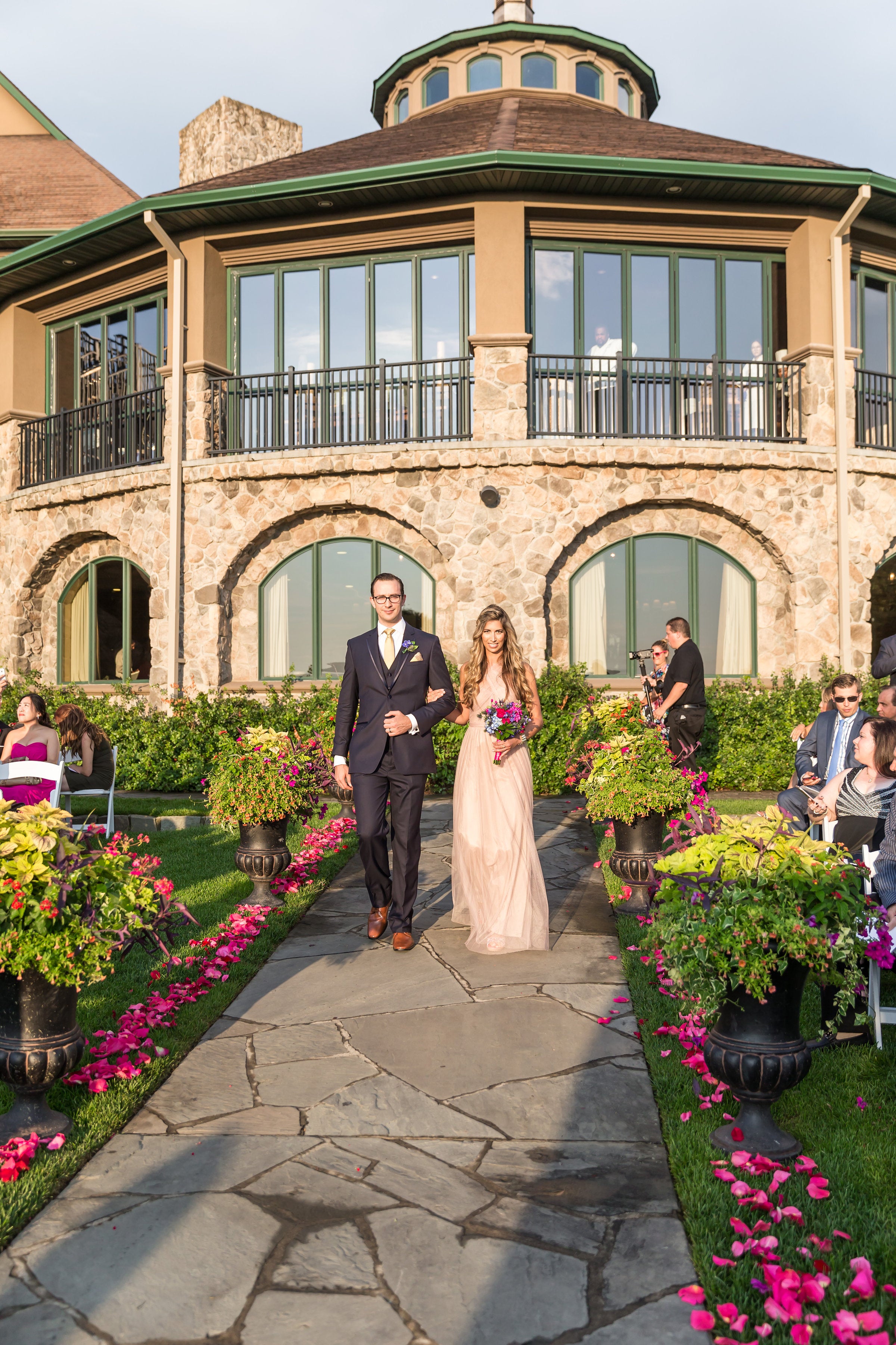 Bridesmaid and groomsmen walk arm in arm down path from Grand Cascades Lodge.