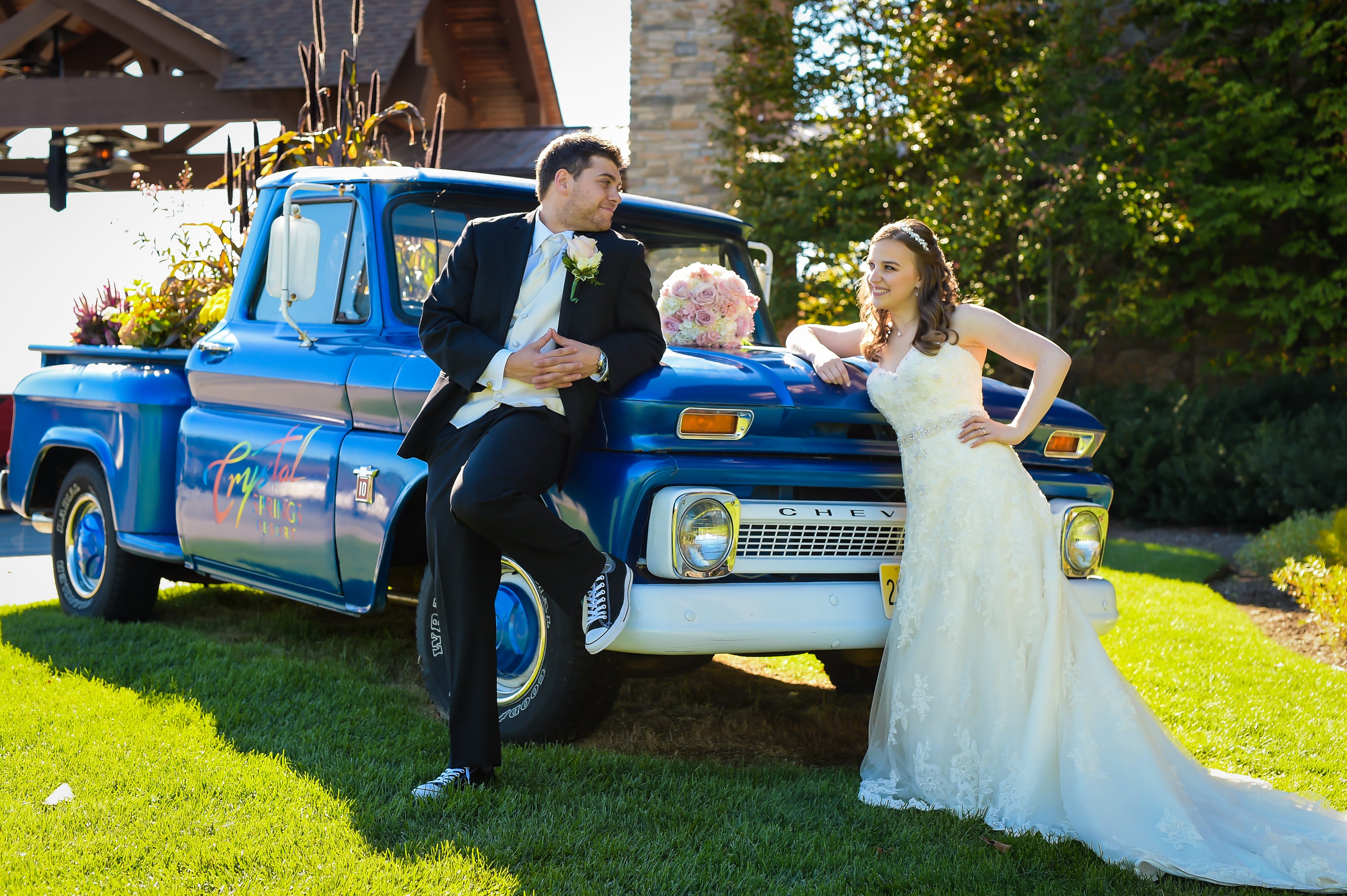 Bride and groom lean on Crystal Springs Resort blue truck