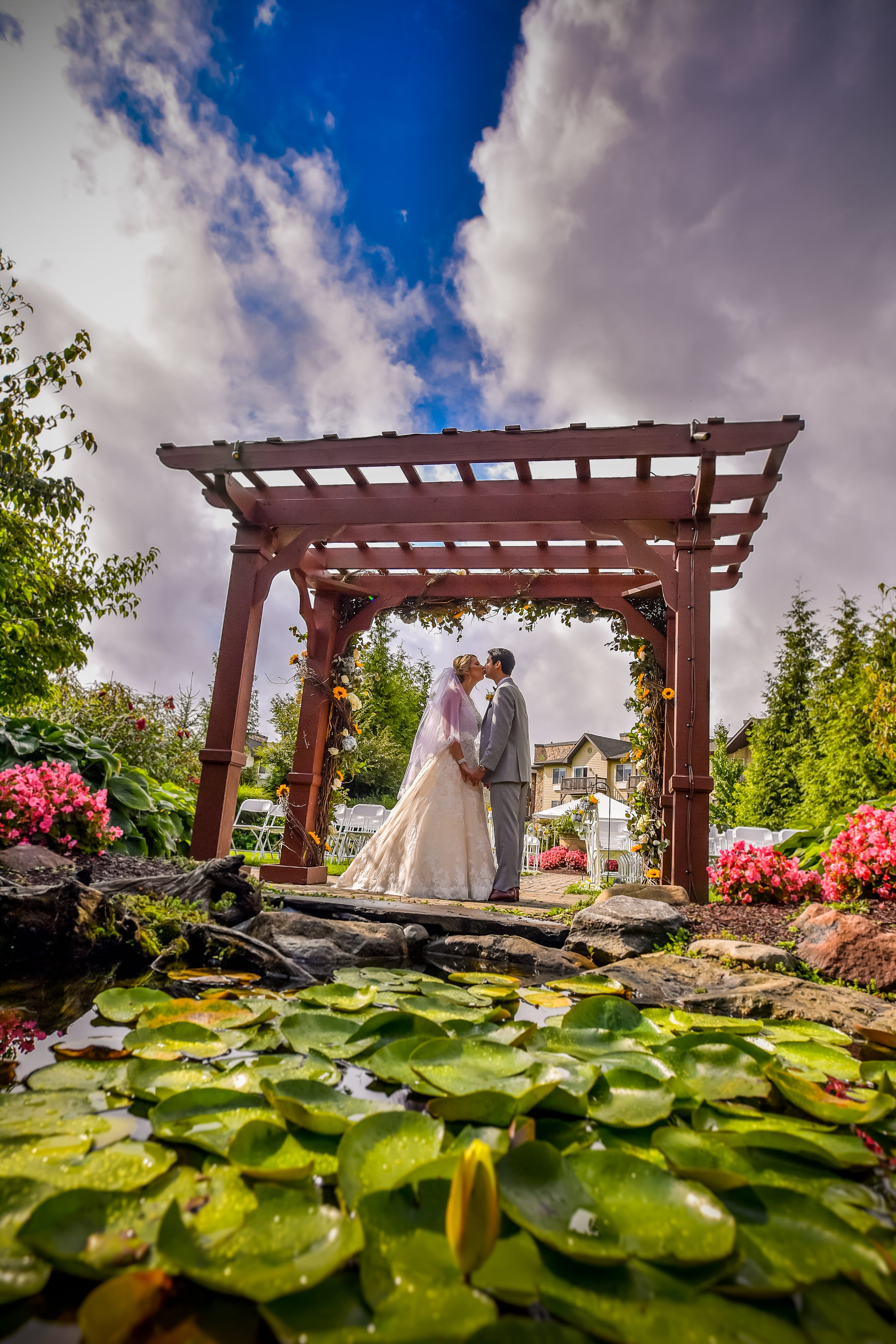 Bride and groom kiss under ceremony arch.