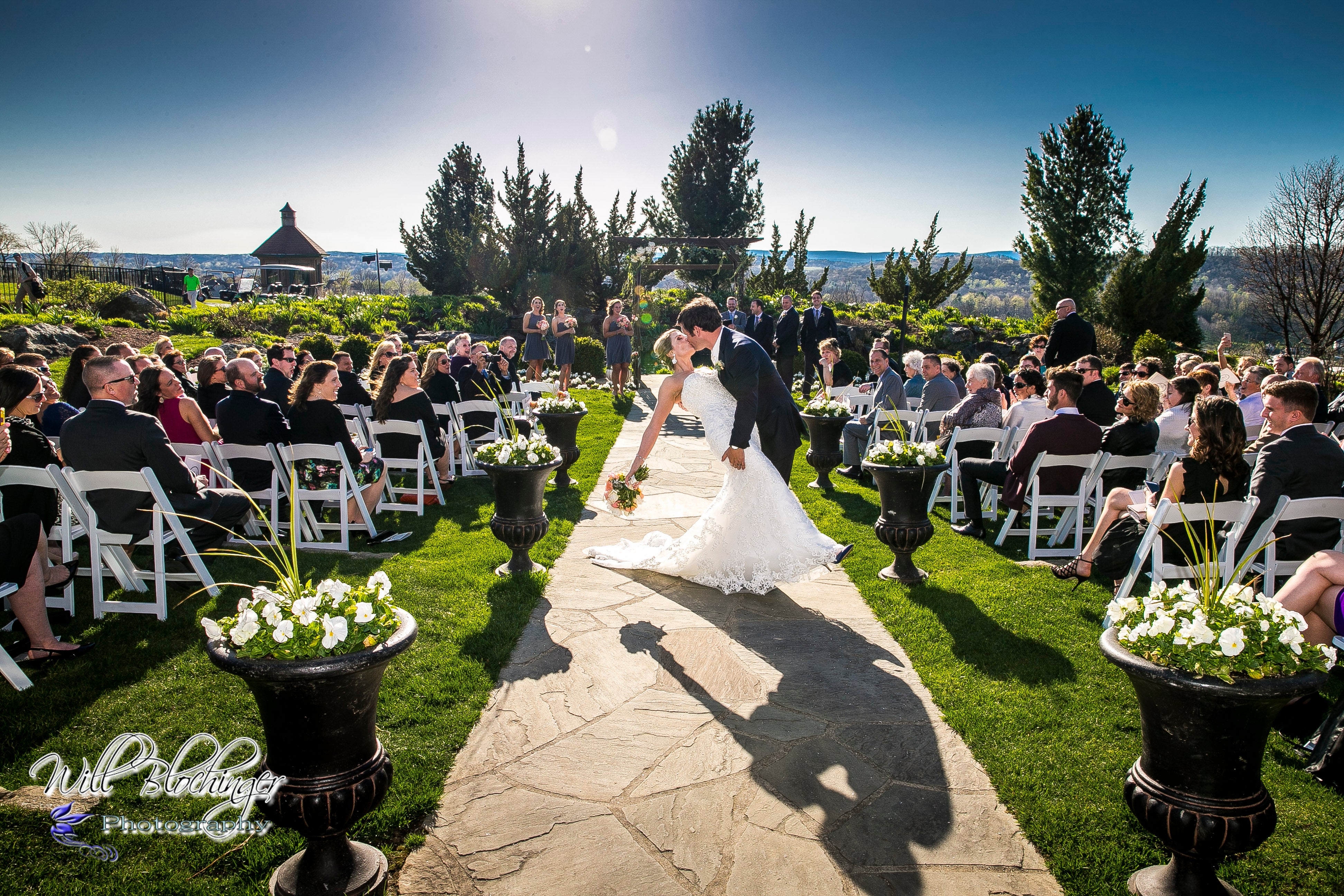 Groom dips bride and kisses her during wedding ceremony.