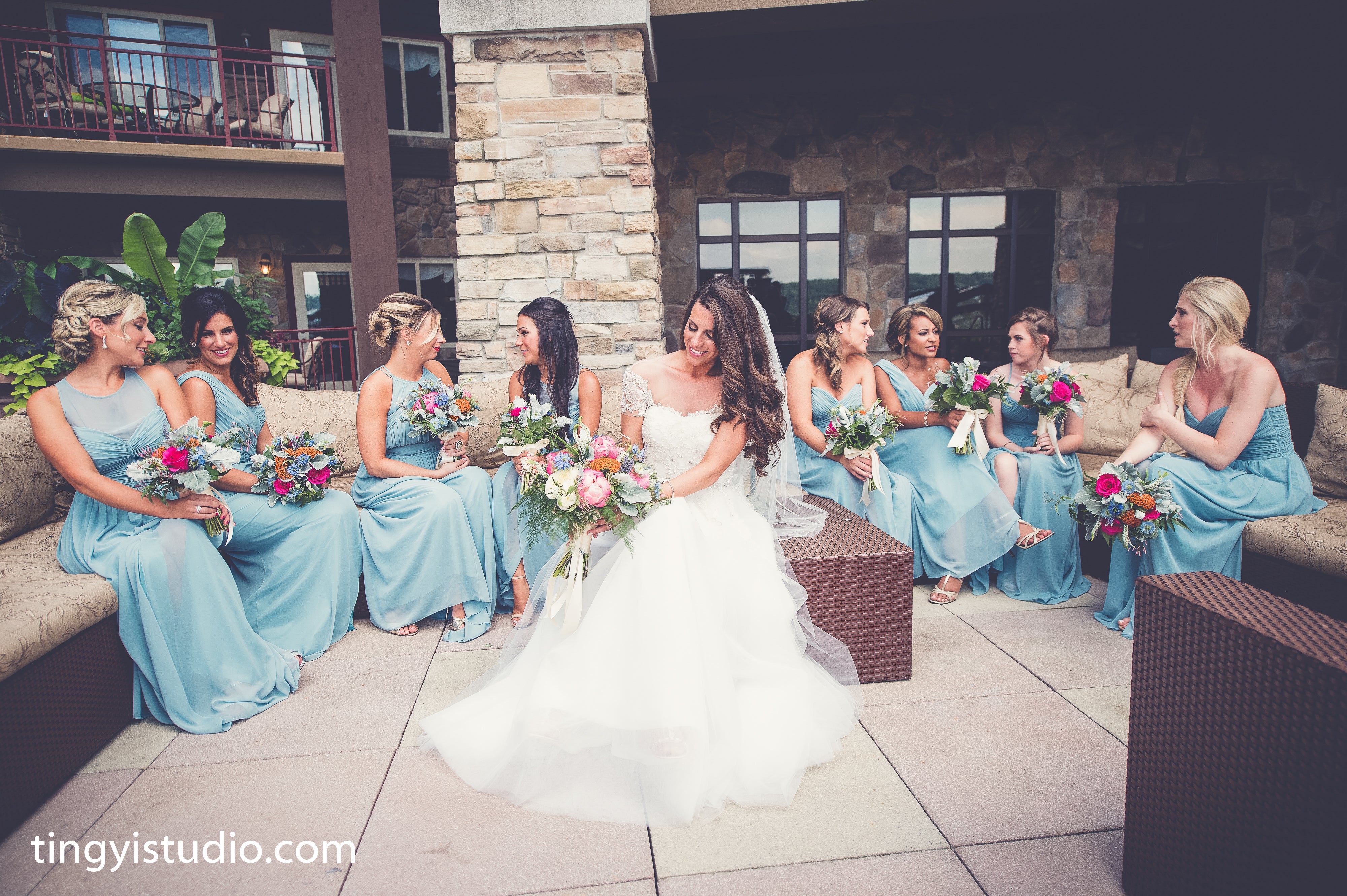 Bride and her bridesmaids, who are wearing light blue dresses, sit on Fire &amp; Water Terrace at Grand Cascades Lodge.