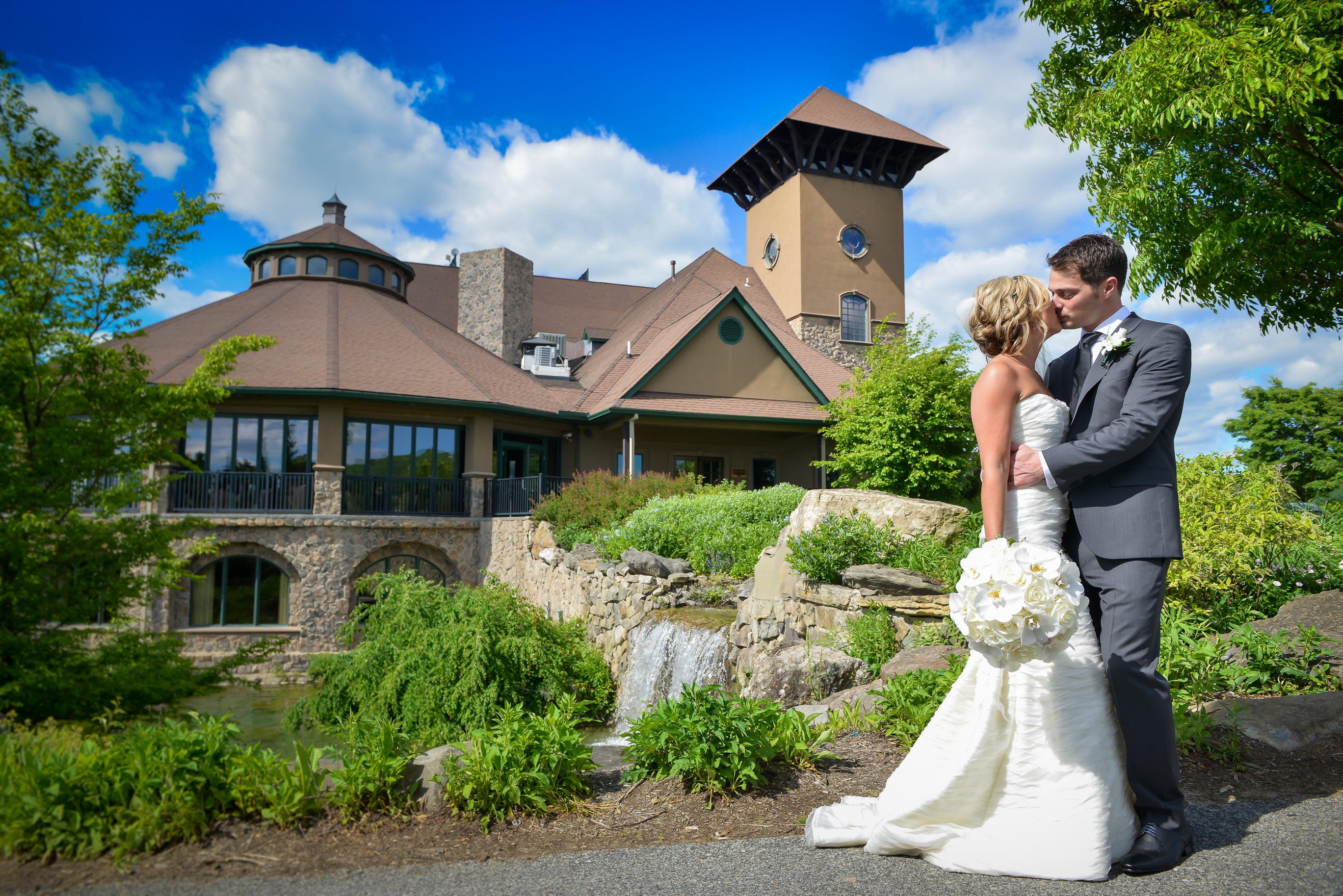 Bride and groom kissing in front of Crystal Springs Country Club