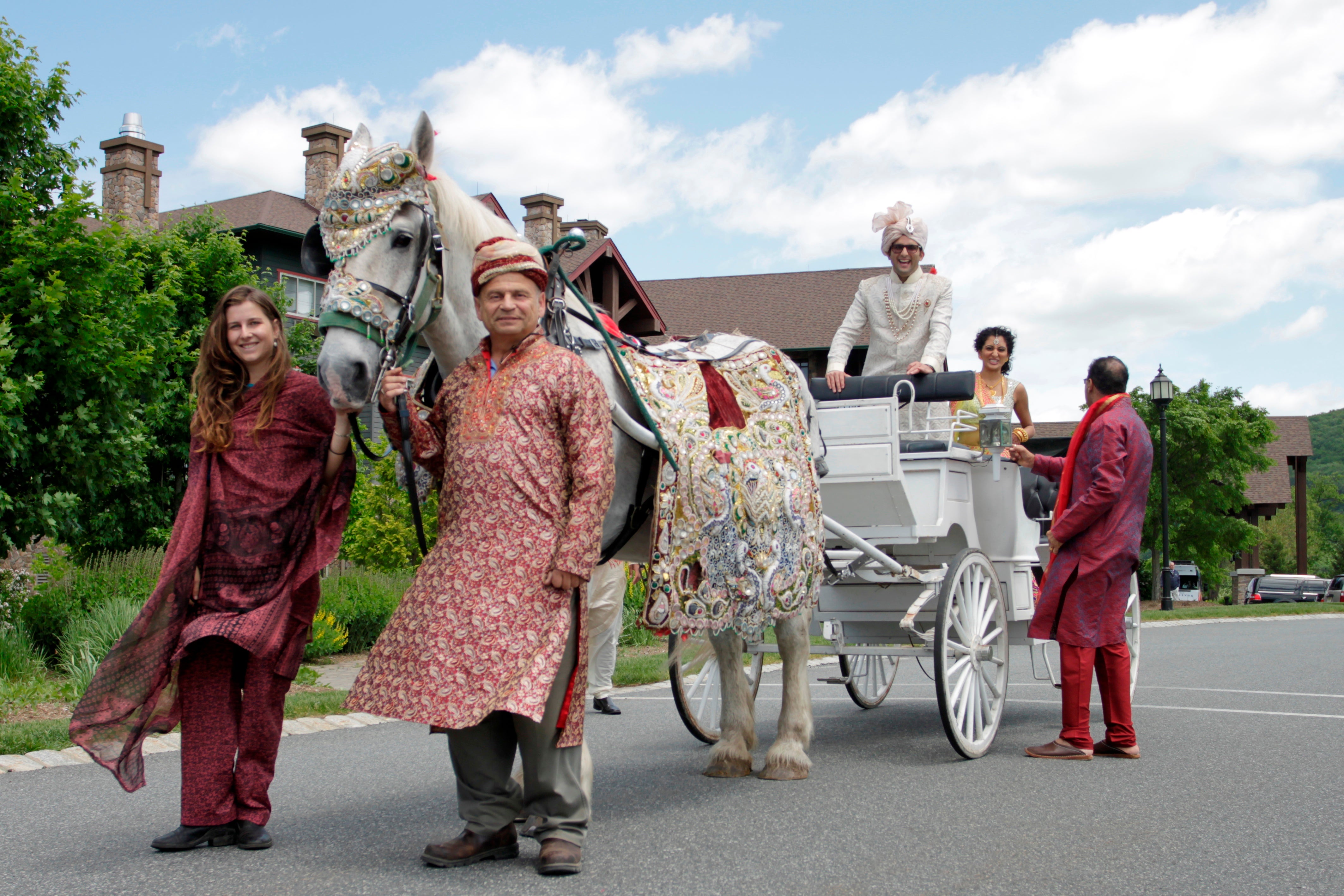 Indian groom riding in carriage behind white horse
