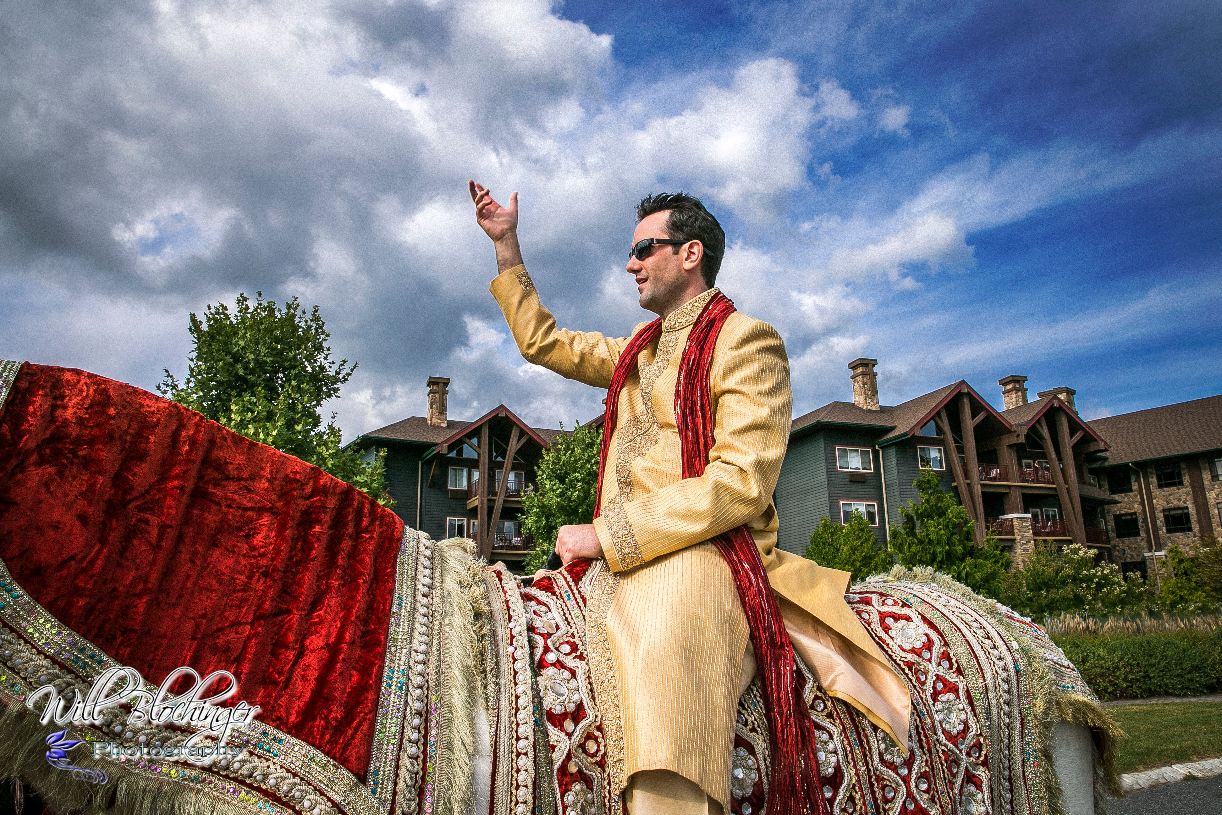 Indian groom riding white horse