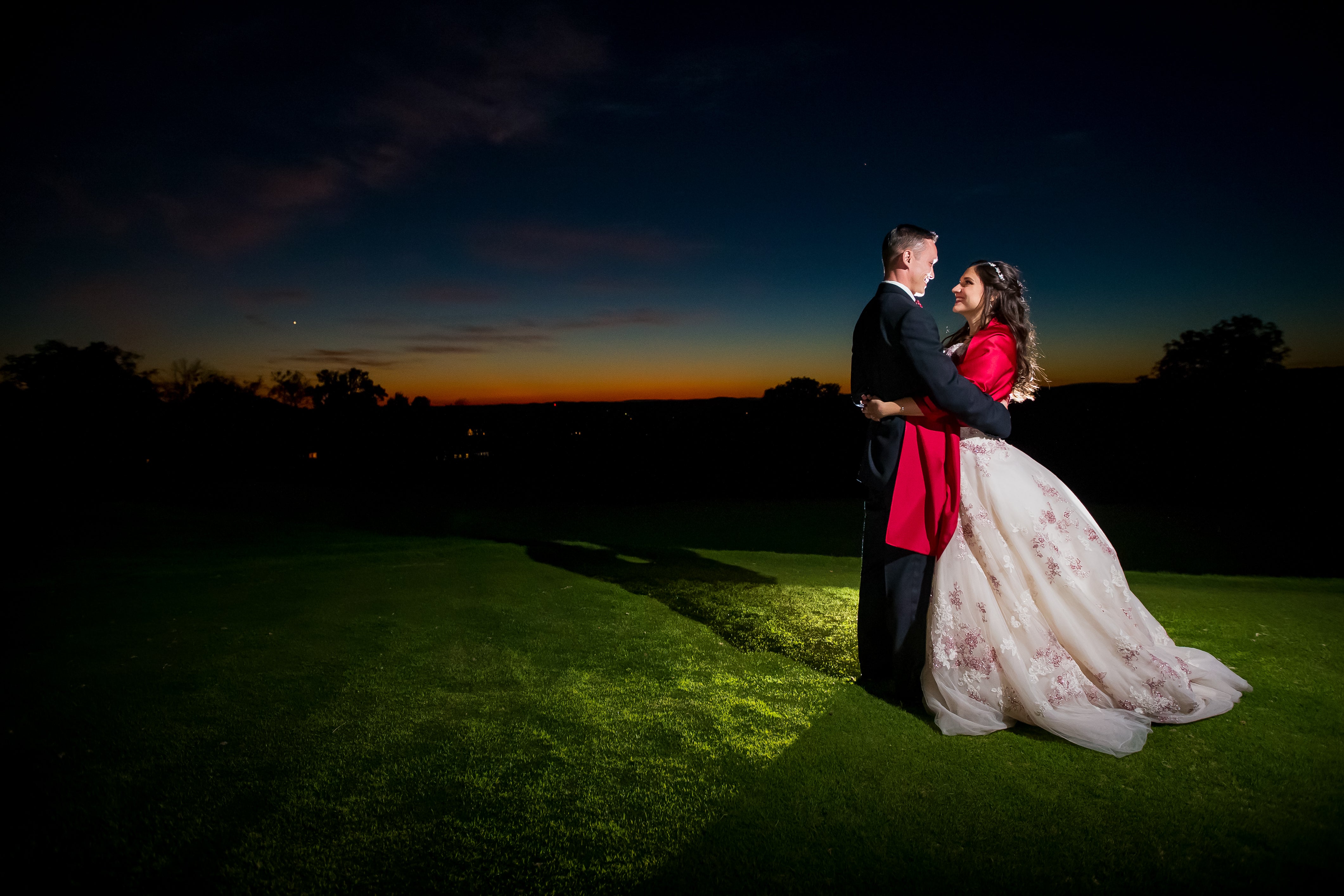 Bride and groom hug during sunset.
