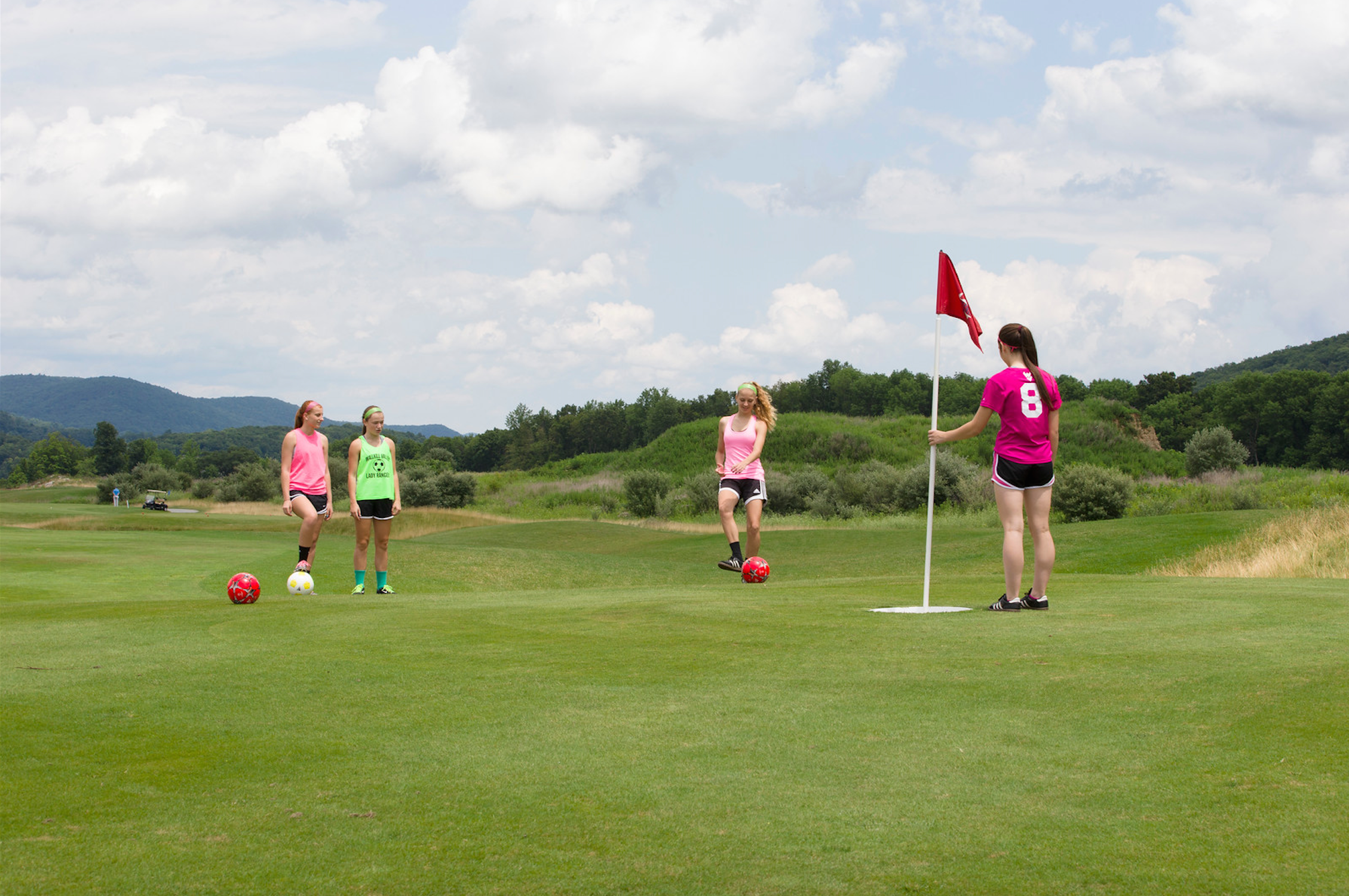 Four girls on a golf course at a resort near NYC playing foot golf