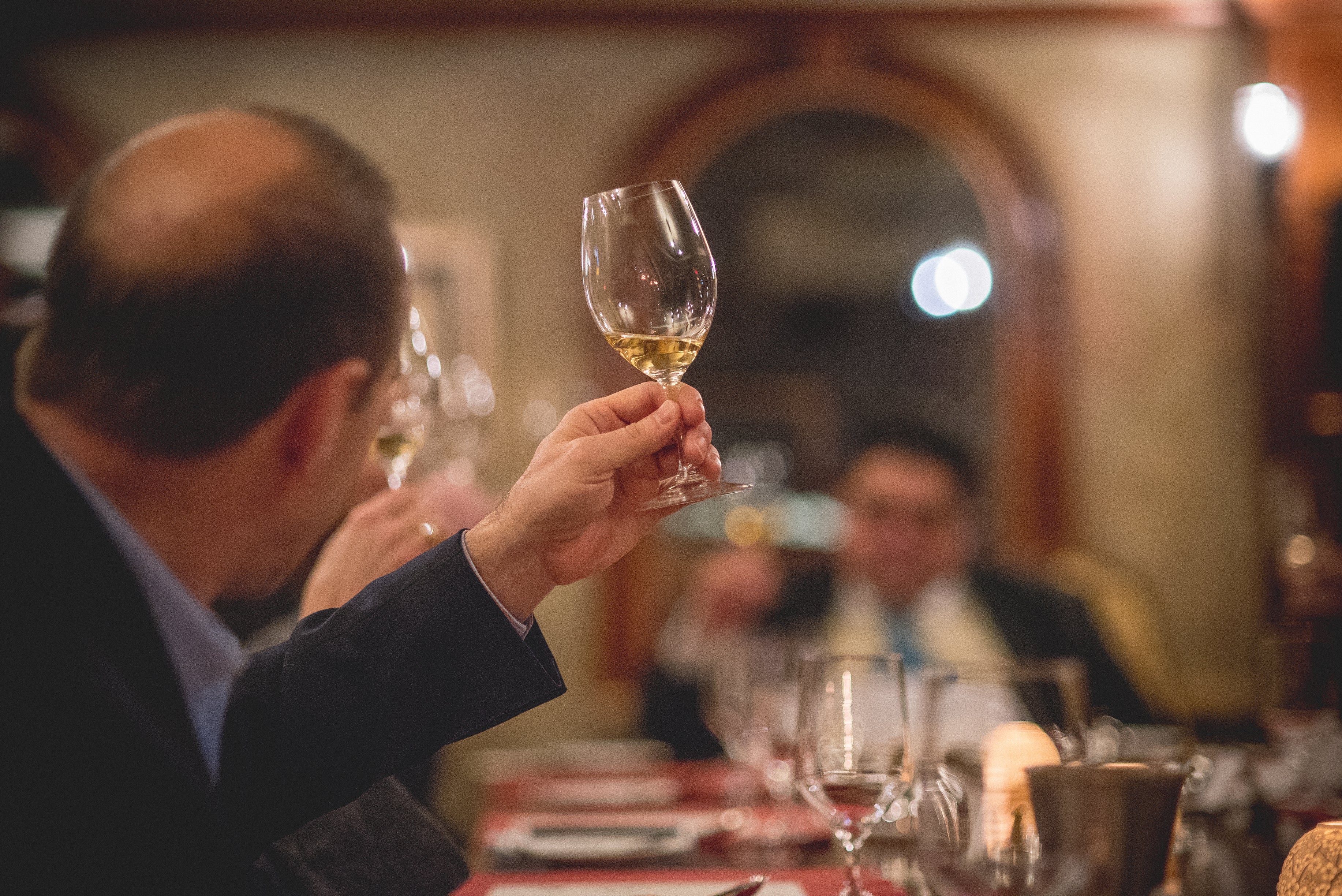 Man holding up glass filled with white wine.