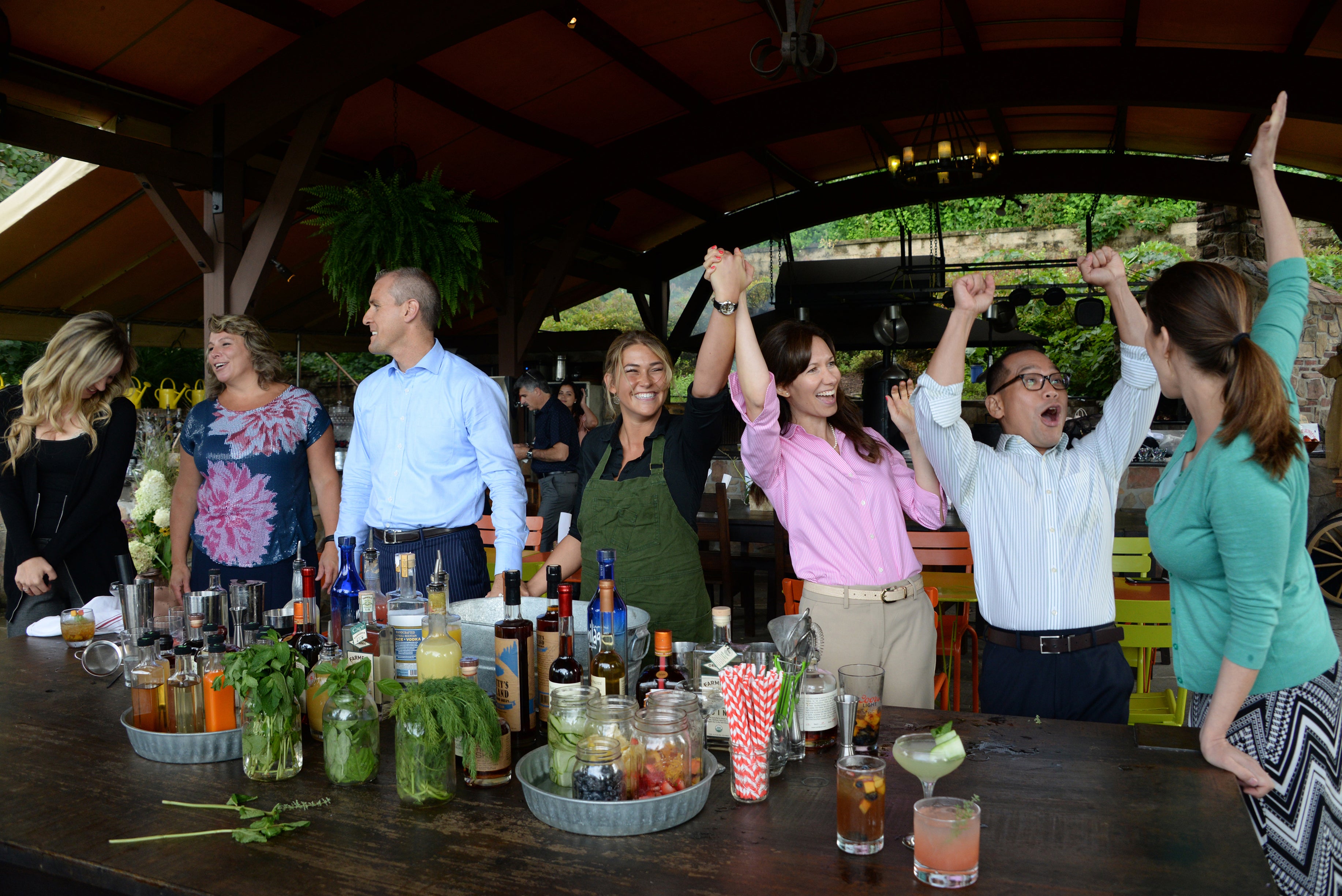 Coworkers cheering as they compete in a mixology teambuilding activity.