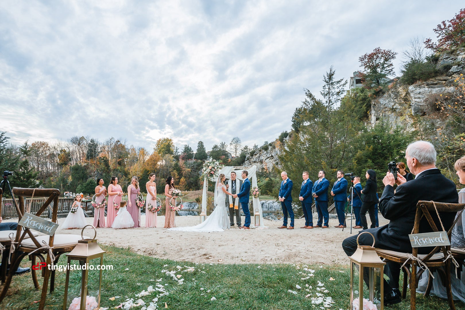Bride and groom standing at alter with bridesmaids and groomsmen