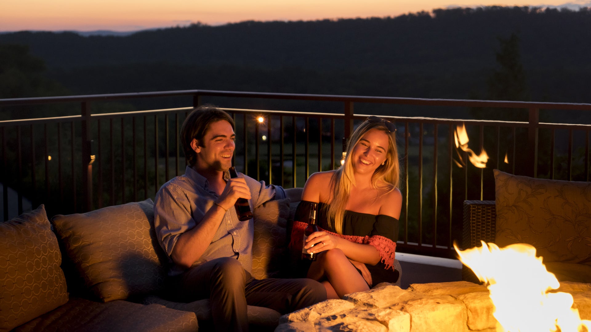 Couple enjoying drinks by the fire pit at Grand Cascades Lodge